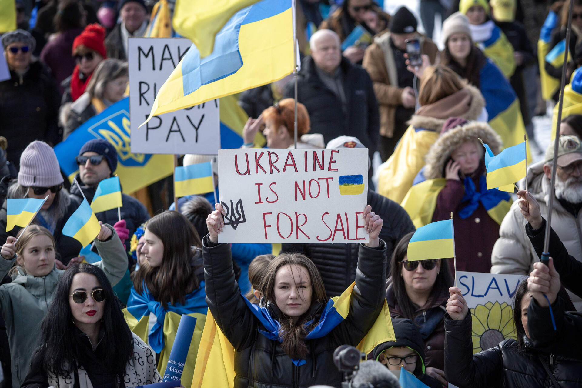 A demonstrator holds up a sign saying "Ukraine is not for sale." (Robin Lubbock/WBUR)