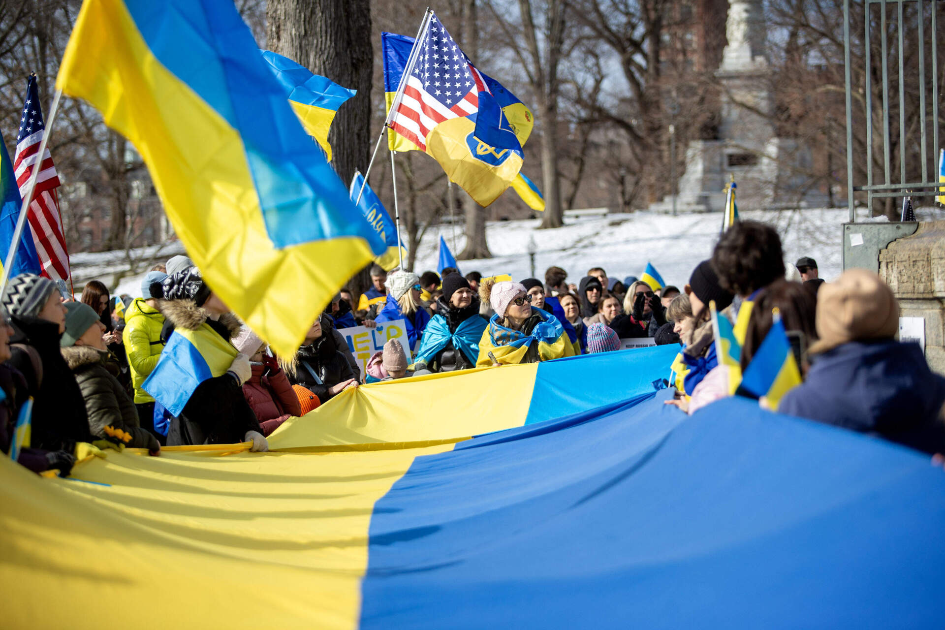 Demonstrators wave Ukrainian flags as they gather at the Parkman Bandstand. (Robin Lubbock/WBUR)