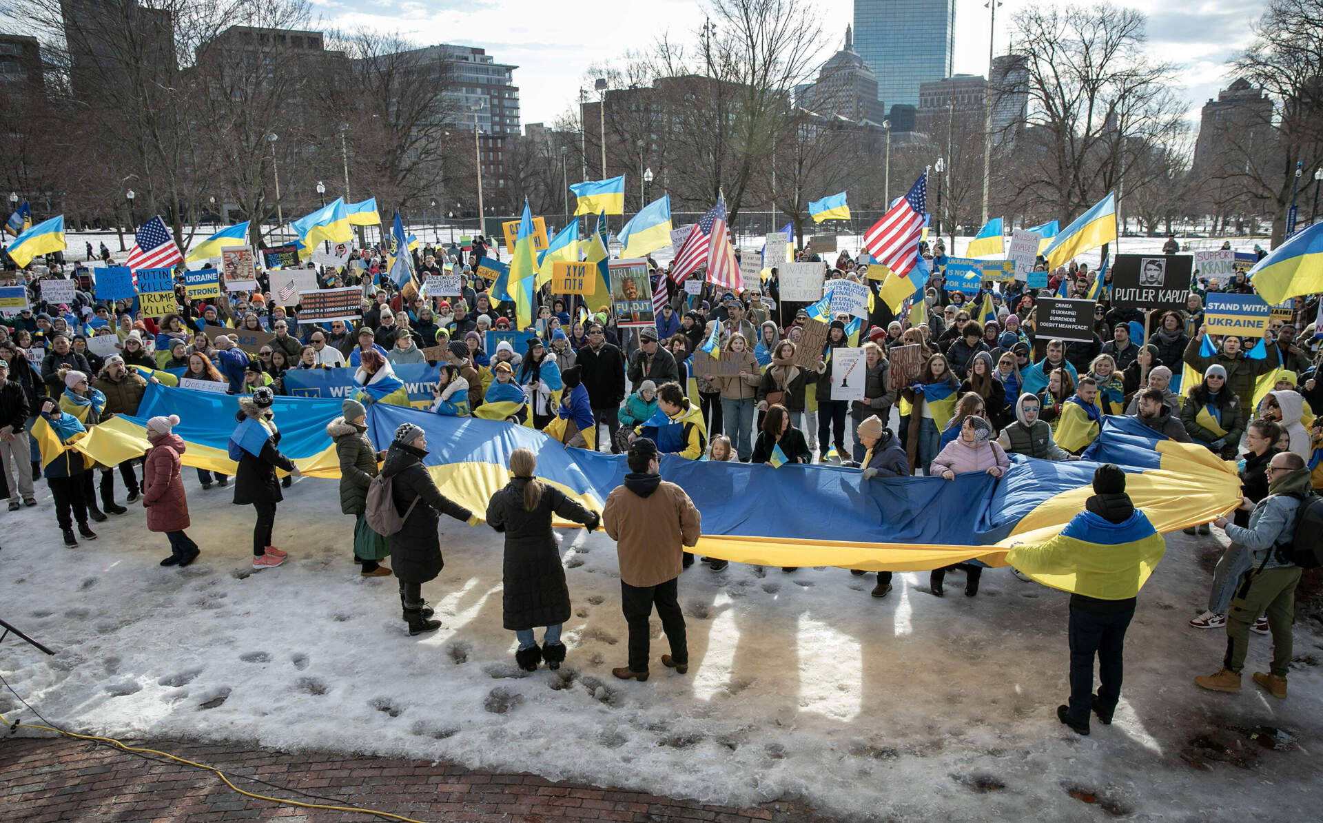 Demonstrators hold up large Ukrainian flag as they gather at the Parkman Bandstand on Boston Common. (Robin Lubbock/WBUR)