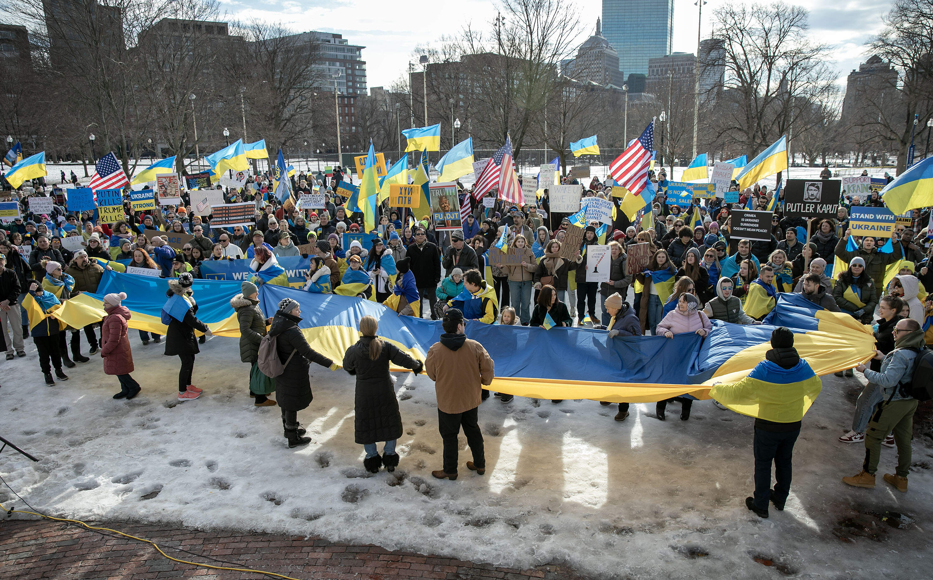Demonstrators hold up large Ukrainian flag as they gather at the Parkman Bandstand on Boston Common. (Robin Lubbock/WBUR)