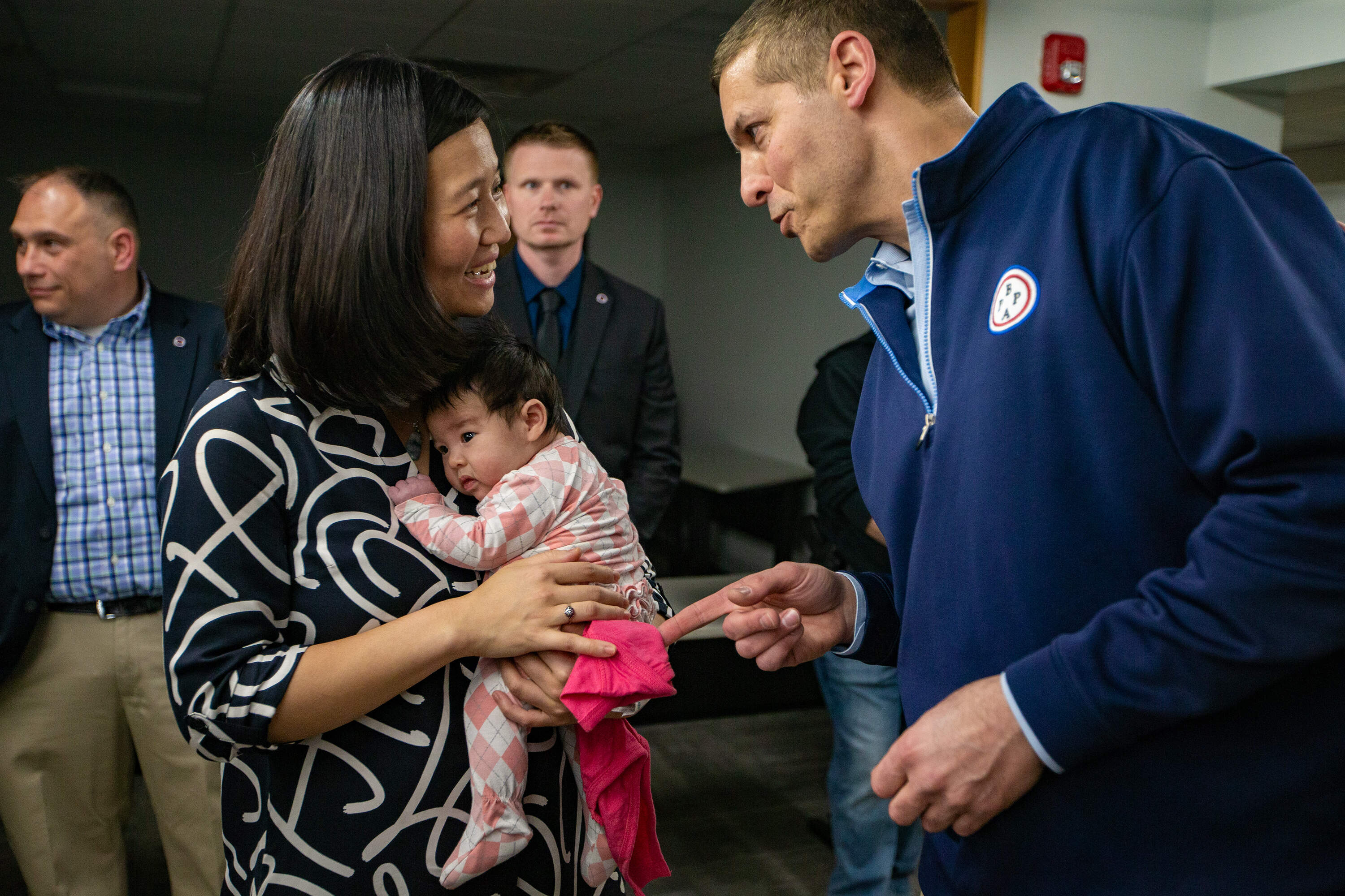 Michelle Wu holds baby Mira in her arms as she speaks with Boston Police Patrolman’s Association President Lawrence Calderone. (Jesse Costa/WBUR)