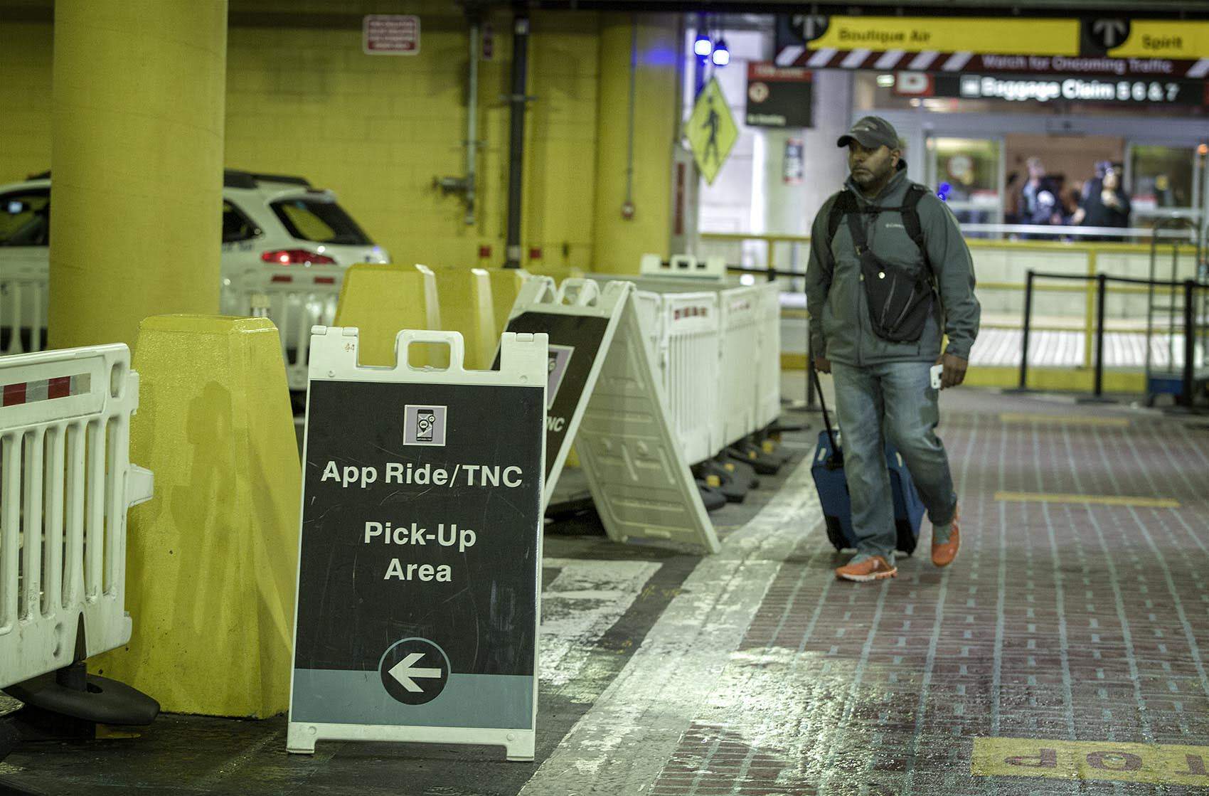 A passenger walks to the app ride pick-up area outside of Terminal B at Logan Airport. (Robin Lubbock/WBUR)