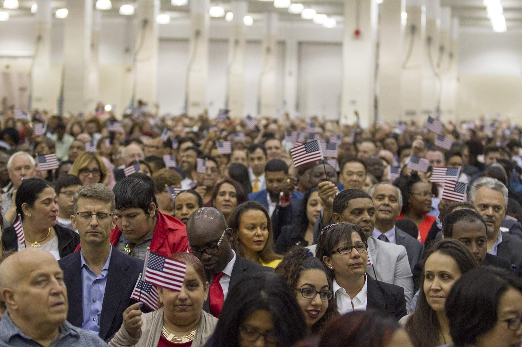 New U.S. citizens wave flags after their oath ceremony at Hynes Convention Center in Boston in 2016. (Joe Difazio for WBUR)