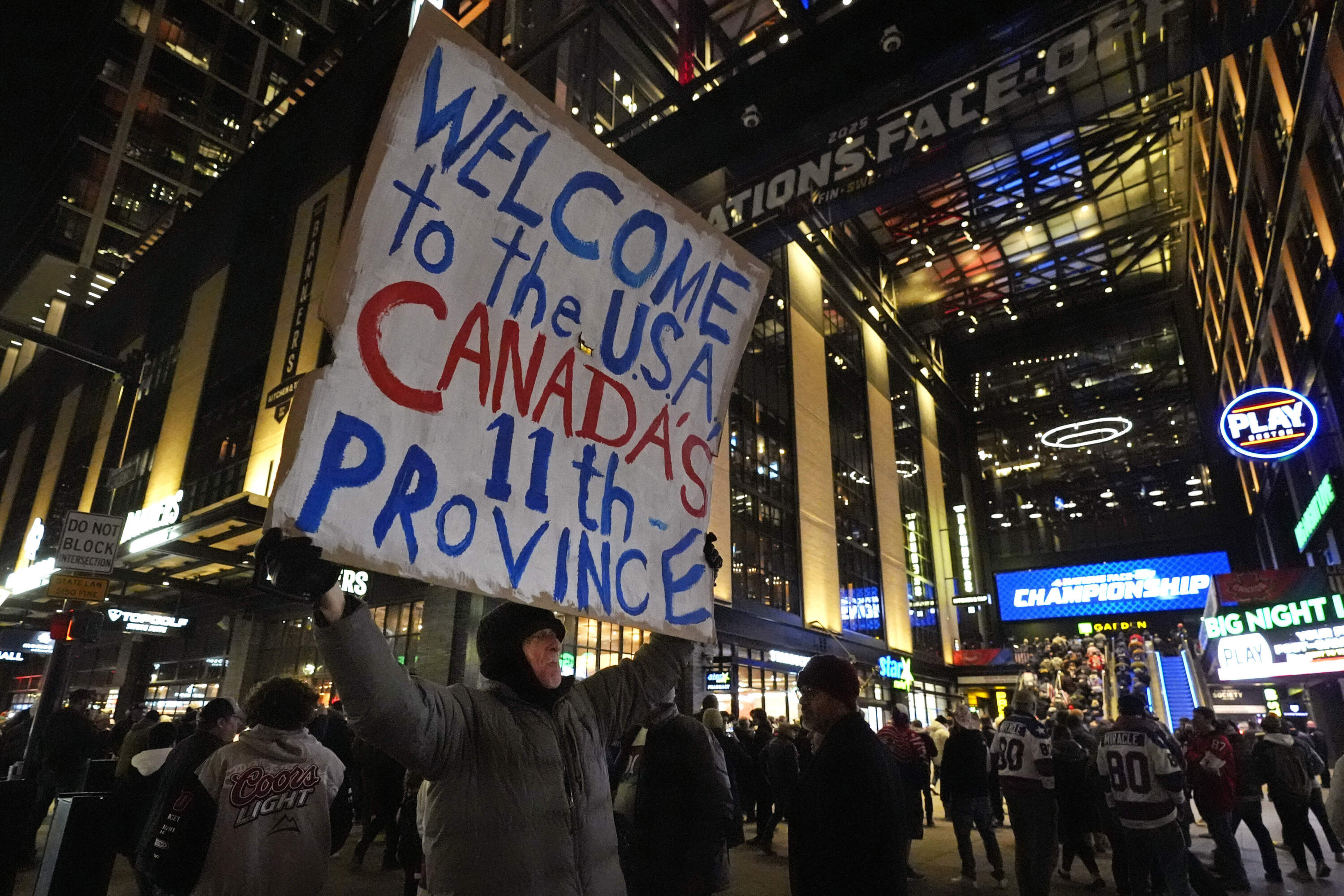 As fans enter TD Garden, a man holds a sign on the sidewalk calling the United States "Canada's 11th province" prior to the 4 Nations Face-Off championship hockey game. (Charles Krupa/AP)