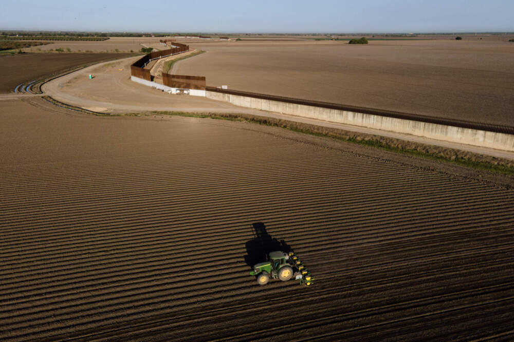 A tractor plows farmland near border wall construction in Progreso, Texas, on March 19, 2021. (Julio Cortez/AP)