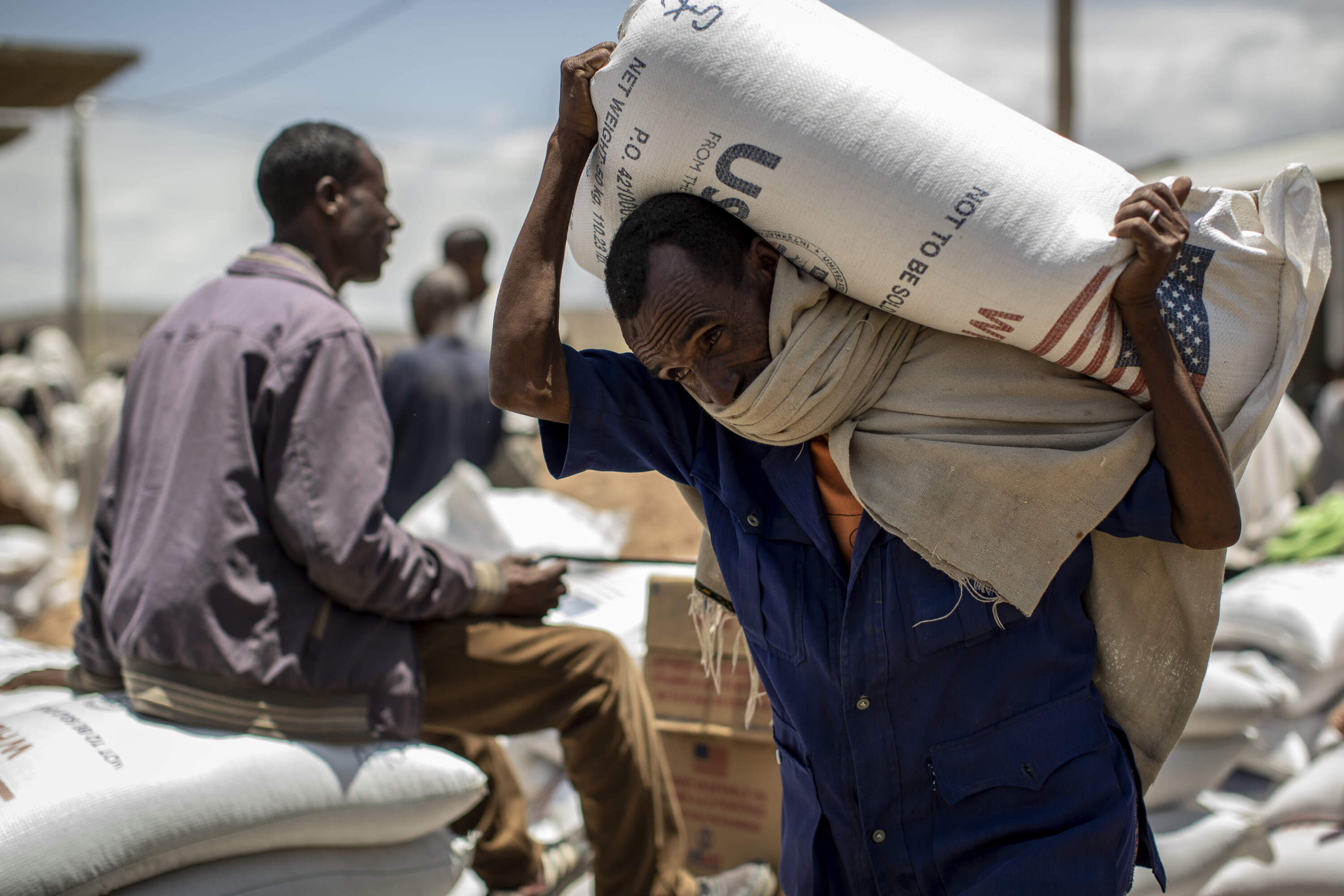 An Ethiopian man carries a USAID donated sack of wheat on his shoulders to be distributed by the Relief Society of Tigray in the town of Agula, in the Tigray region of northern Ethiopia, on Saturday, May 8, 2021. (Ben Curtis/AP)
