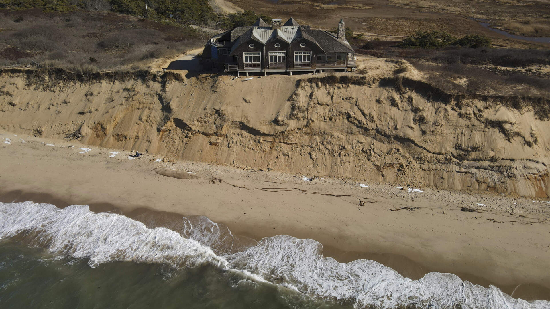 A home sits atop of a sandy bluff overlooking a beach in Wellfleet, Mass., Monday, Jan. 27, 2025. (Andre Muggiati/AP)