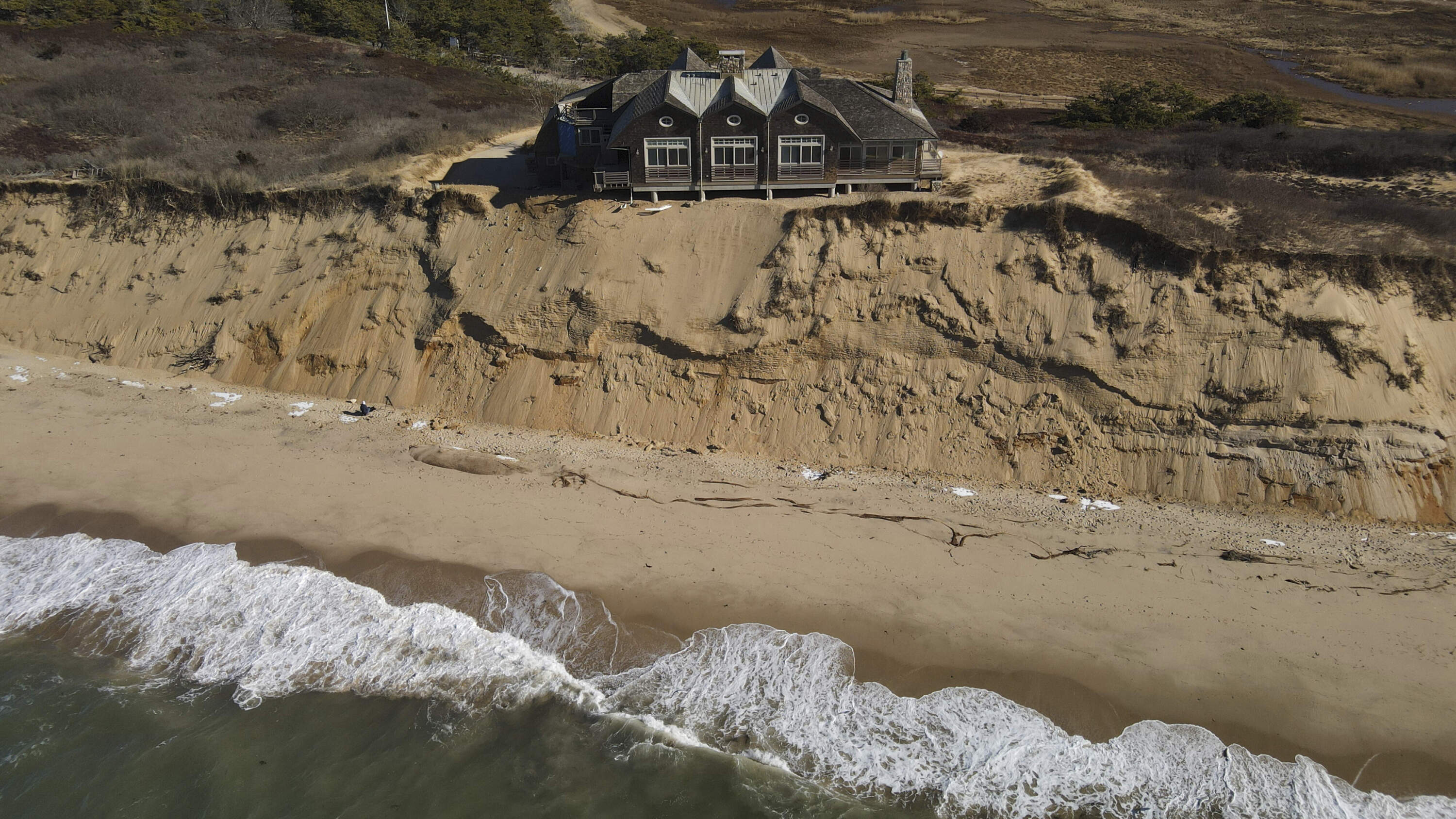 A home sits atop of a sandy bluff overlooking a beach in Wellfleet, Mass., Monday, Jan. 27, 2025. (Andre Muggiati/AP)