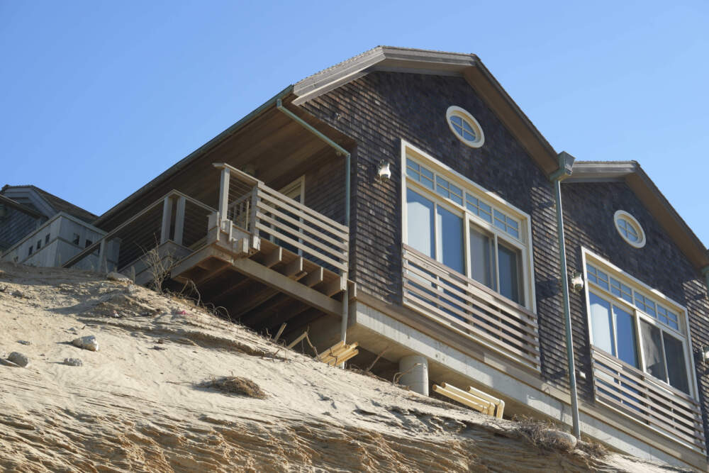The porch of a home hangs over a dune. (Andre Muggiati/AP)