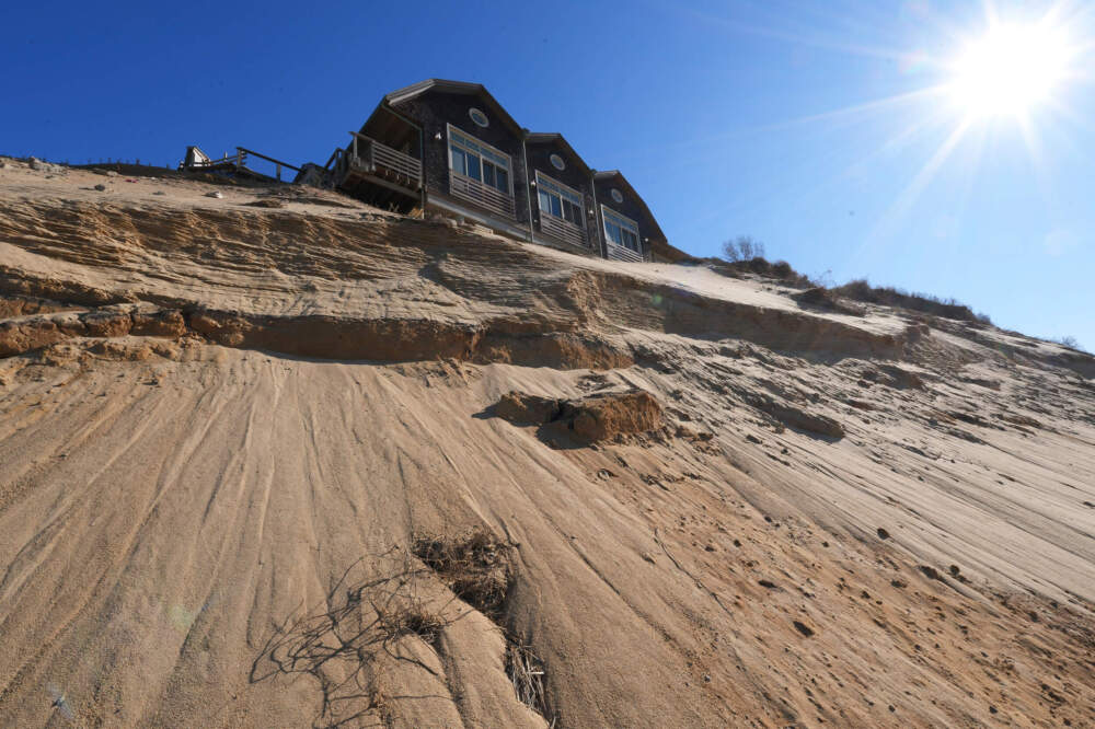 Sand slopes down from beneath a house on the dunes. (Andre Muggiati/AP)