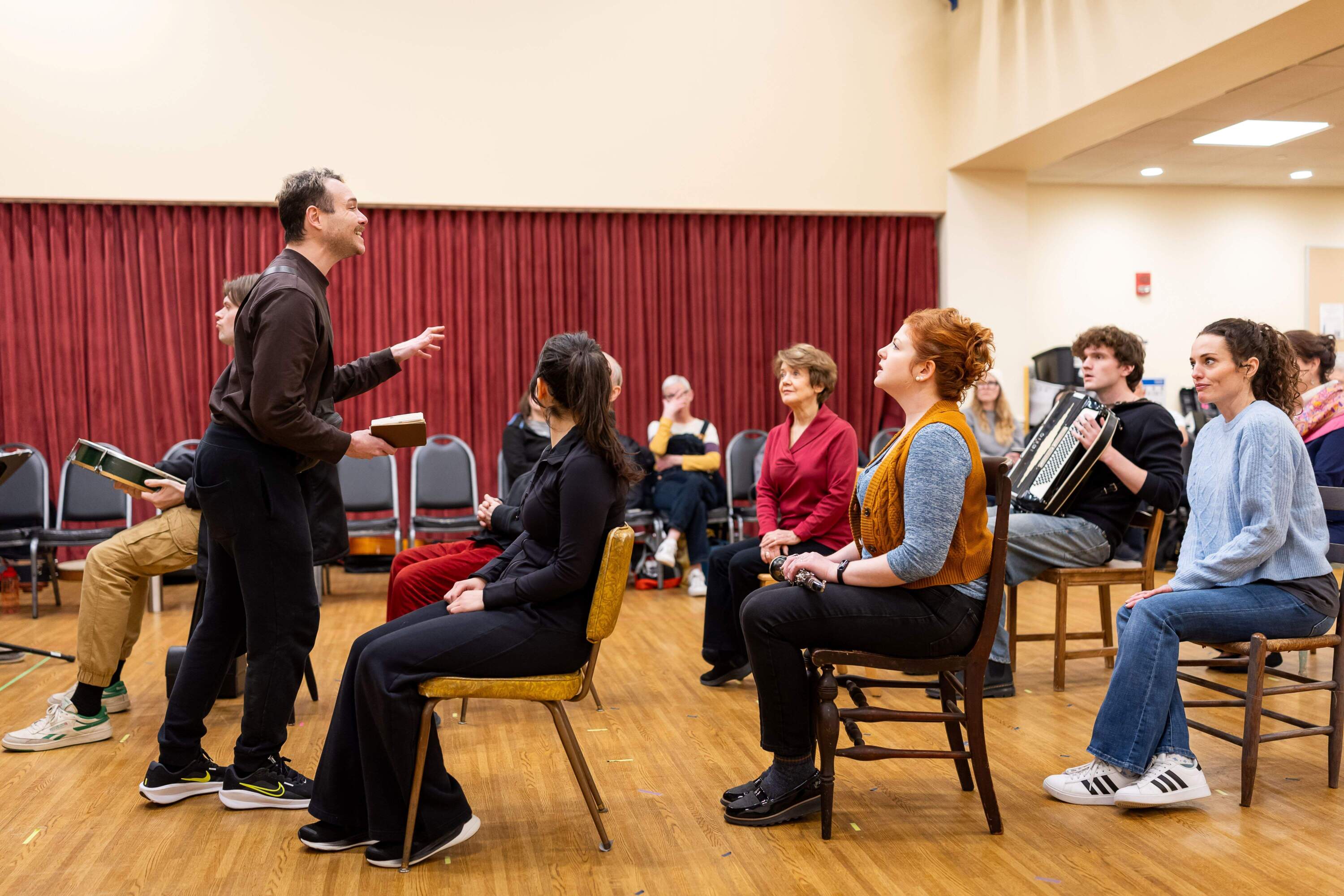 Eddie Shields (standing) reading to passengers on bus during rehearsal for "A Man of No Importance." (Courtesy Nile Scott Studios)