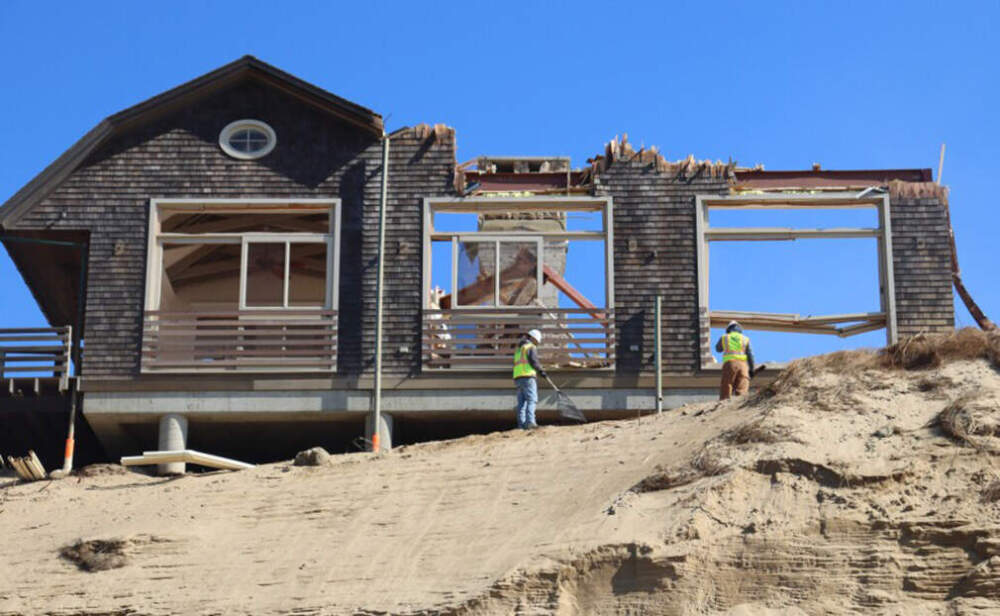Crew members rake debris from below the partially demolished Blasch house. (Eve Zuckoff/CAI)