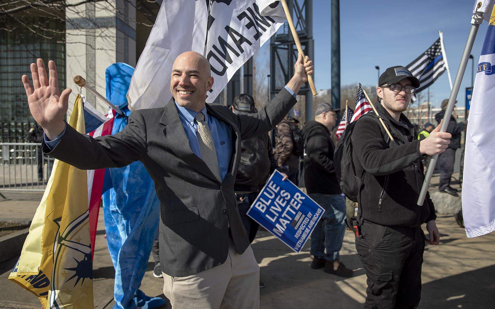 Samson Racioppi, then-chairman of Super Happy Fun America, waves at passing cars during a rally outside Boston Police Department headquarters in February 2020. (Robin Lubbock/WBUR)