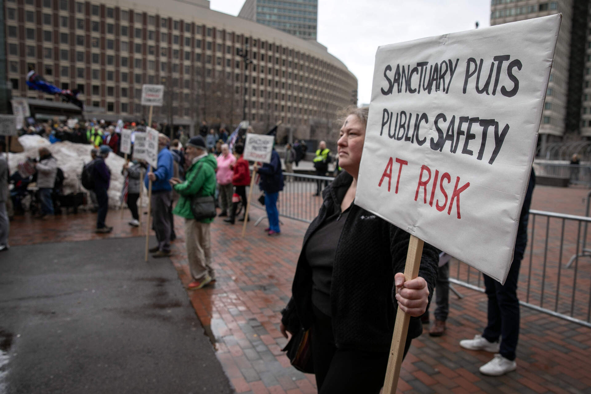A counter-protester stands at the edge of a rally of supporters of Mayor Michelle Wu outside Boston's City Hall while she appeared before Congress. (Robin Lubbock/WBUR)