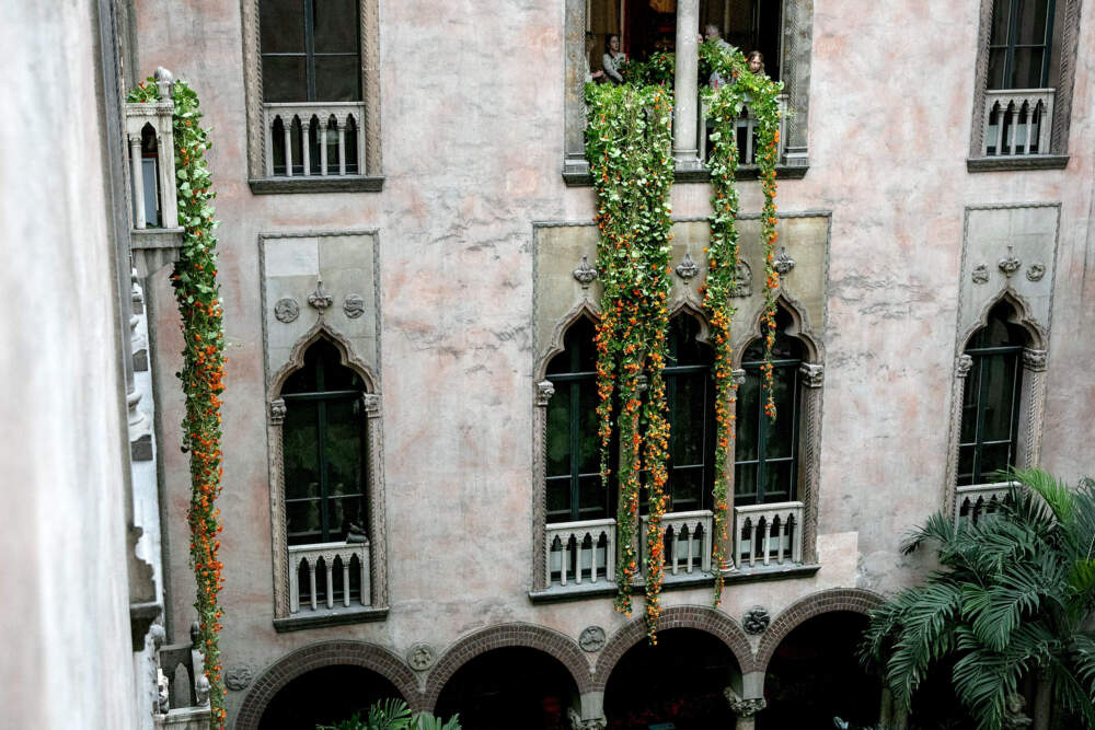 Horticulturalists lower vines of nasturtiums through a window of the Titian Room at the Isabella Stewart Gardner Museum in Boston. (Robin Lubbock/WBUR)