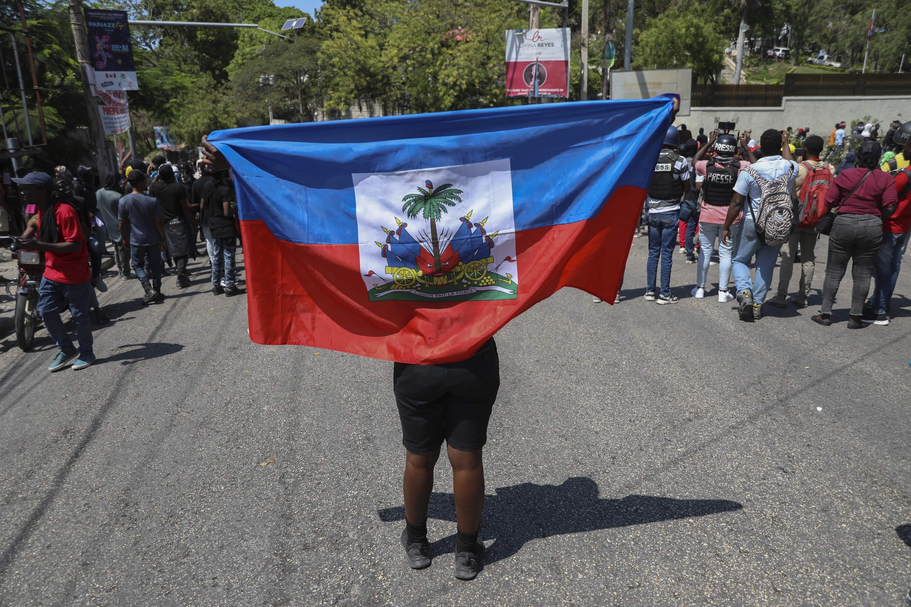 A protester holds a Haitian flag during a demonstration in Haiti. Haitians living in the U.S. may have to return to the gang-ridden nation after President Trump rescinded a parole program. (Odelyn Joseph/AP)