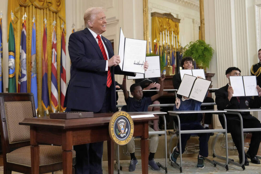 President Trump holds up a signed executive order as young people hold up copies of the executive order they signed in the White House on Thursday. (Ben Curtis/AP)