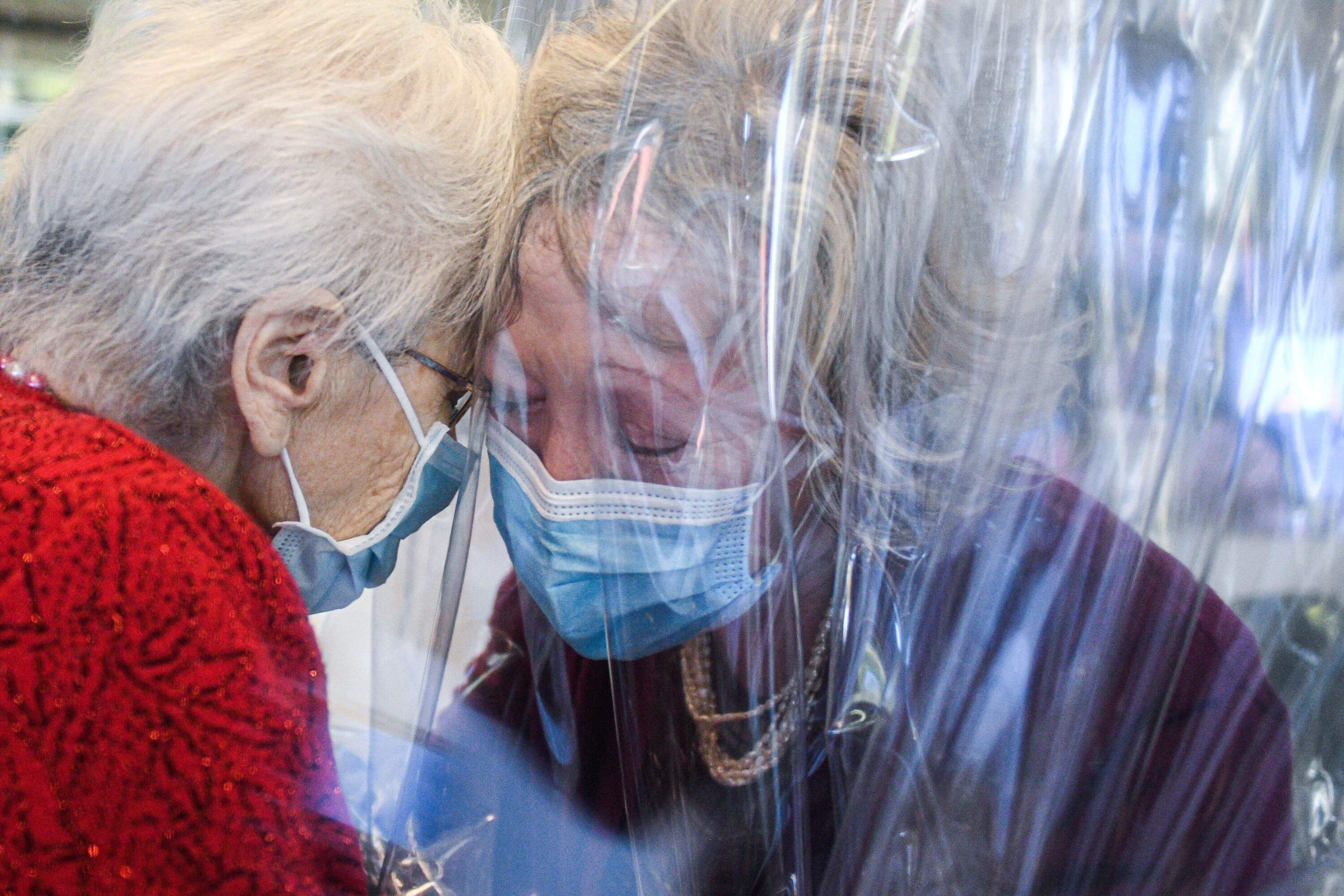 A resident (L) of the Domenico Sartor nursing home in Castelfranco Veneto, near Venice, hugs her visiting daughter on Nov. 11, 2020 through a plastic screen in a so-called "Hug Room" amid the new coronavirus pandemic. (Piero Cruciatti/AFP via Getty Images)