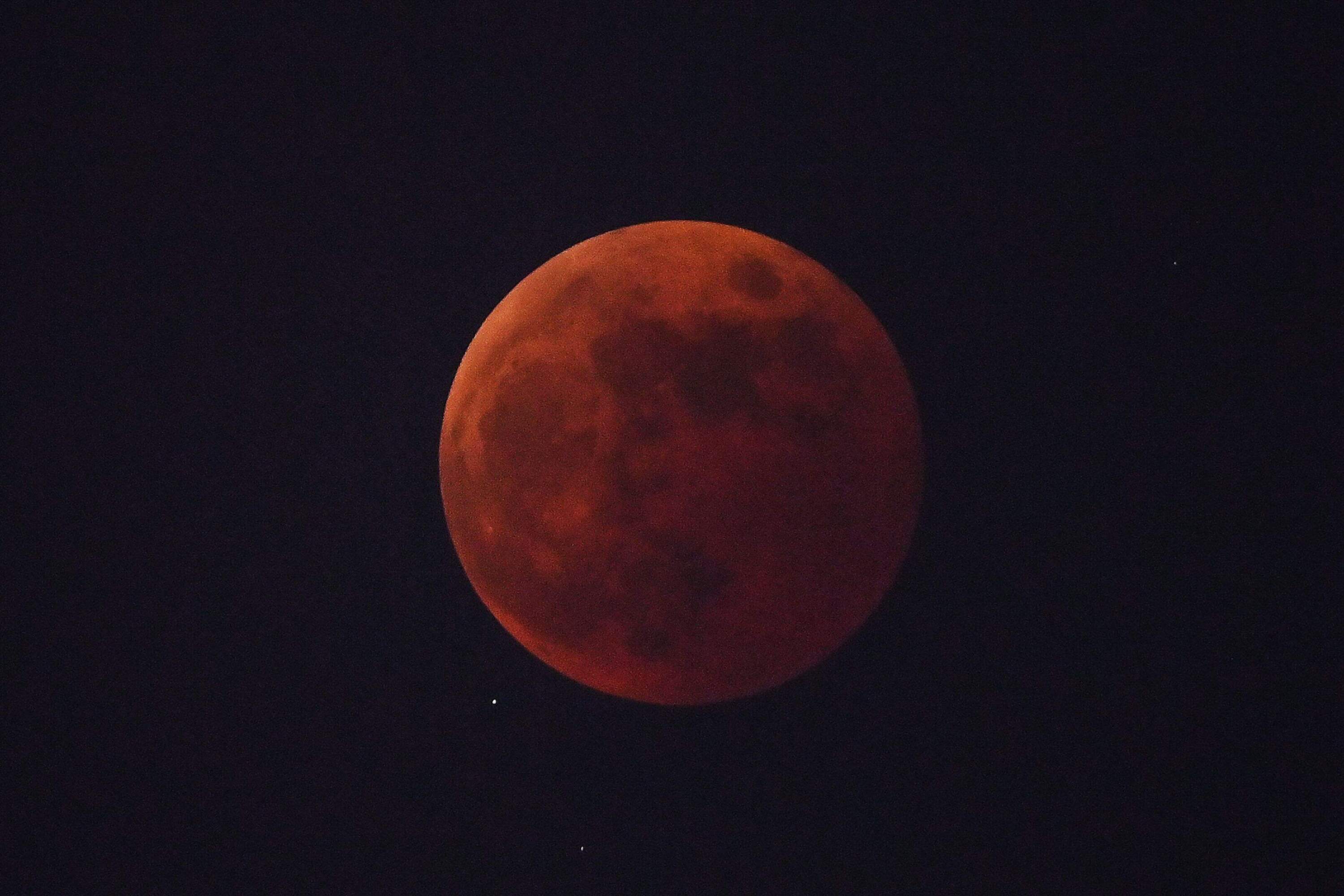 The 'Blood Moon' is seen from The Bund promende during a total lunar eclipse in Shanghai on Nov. 8, 2022. (Photo by Hector Retamal/AFP via Getty Images)