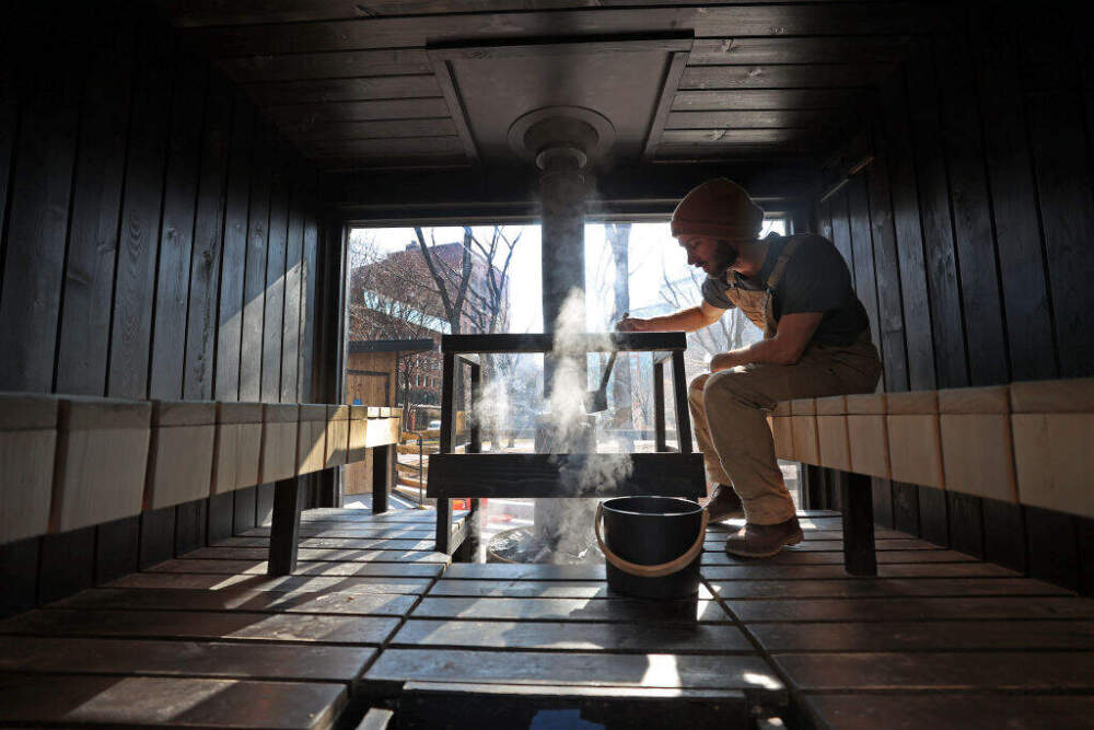 Ty Hendrix, operations manager at the MOKI Sauna Village, makes some steam with water on hot rocks getting the sauna ready for a customer. (Photo by David L. Ryan/The Boston Globe via Getty Images)