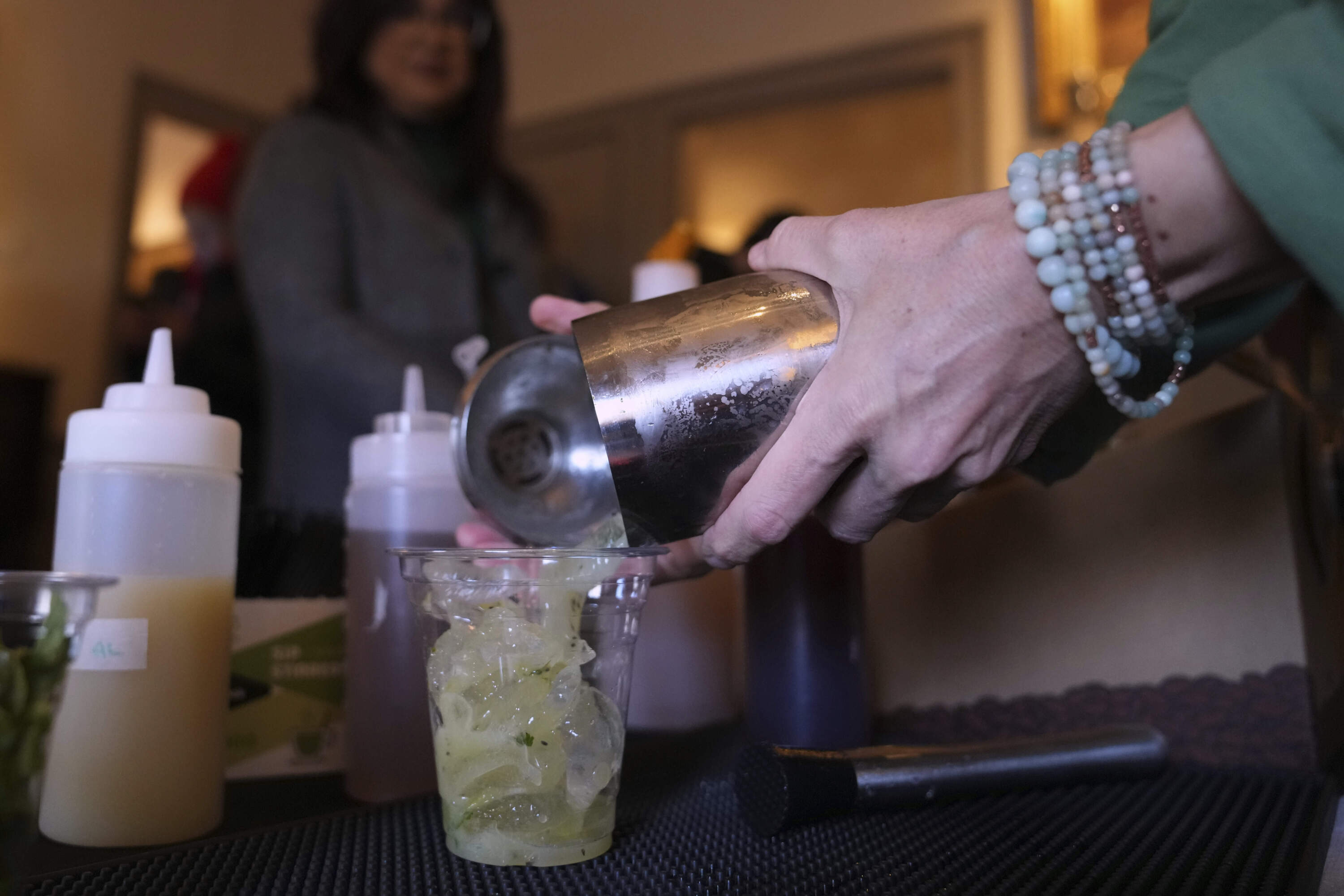 Jeanmarie Holmes of the Dragonfly Cafe pours a Kiwi Mule mocktail, made without tequila, during the sober Saint Patrick's Day celebration at the Whistler House Museum, Thursday, March 13, 2025, in Lowell, Mass. (Charles Krupa/AP)