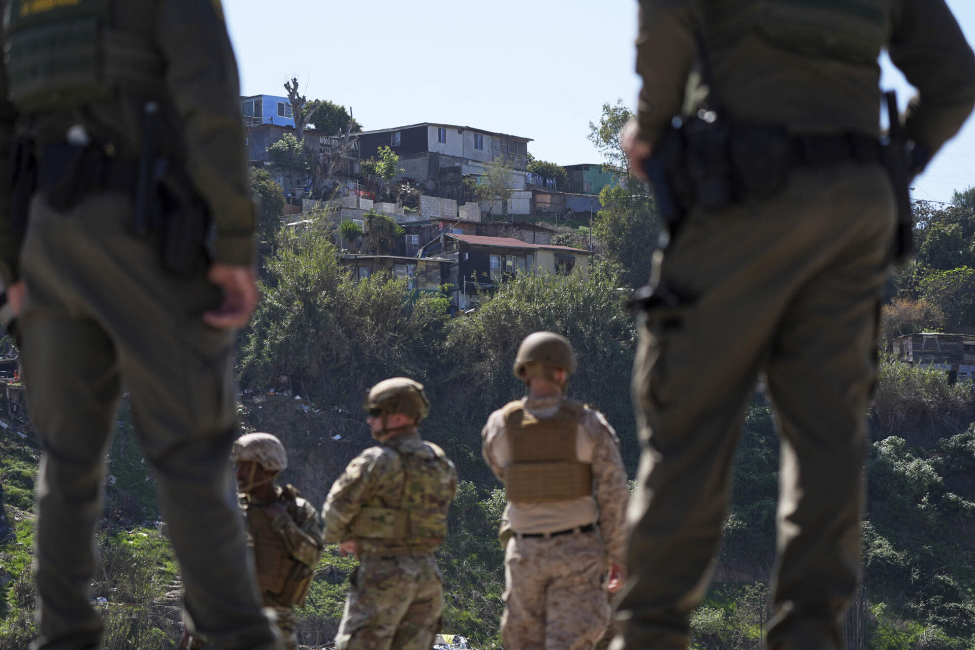 Border Patrol agents and members of the military look toward Tijuana, Mexico, as they stand between two border walls during a news conference on joint operations involving the military and the Border Patrol on March 21 in San Diego. (Gregory Bull/AP)