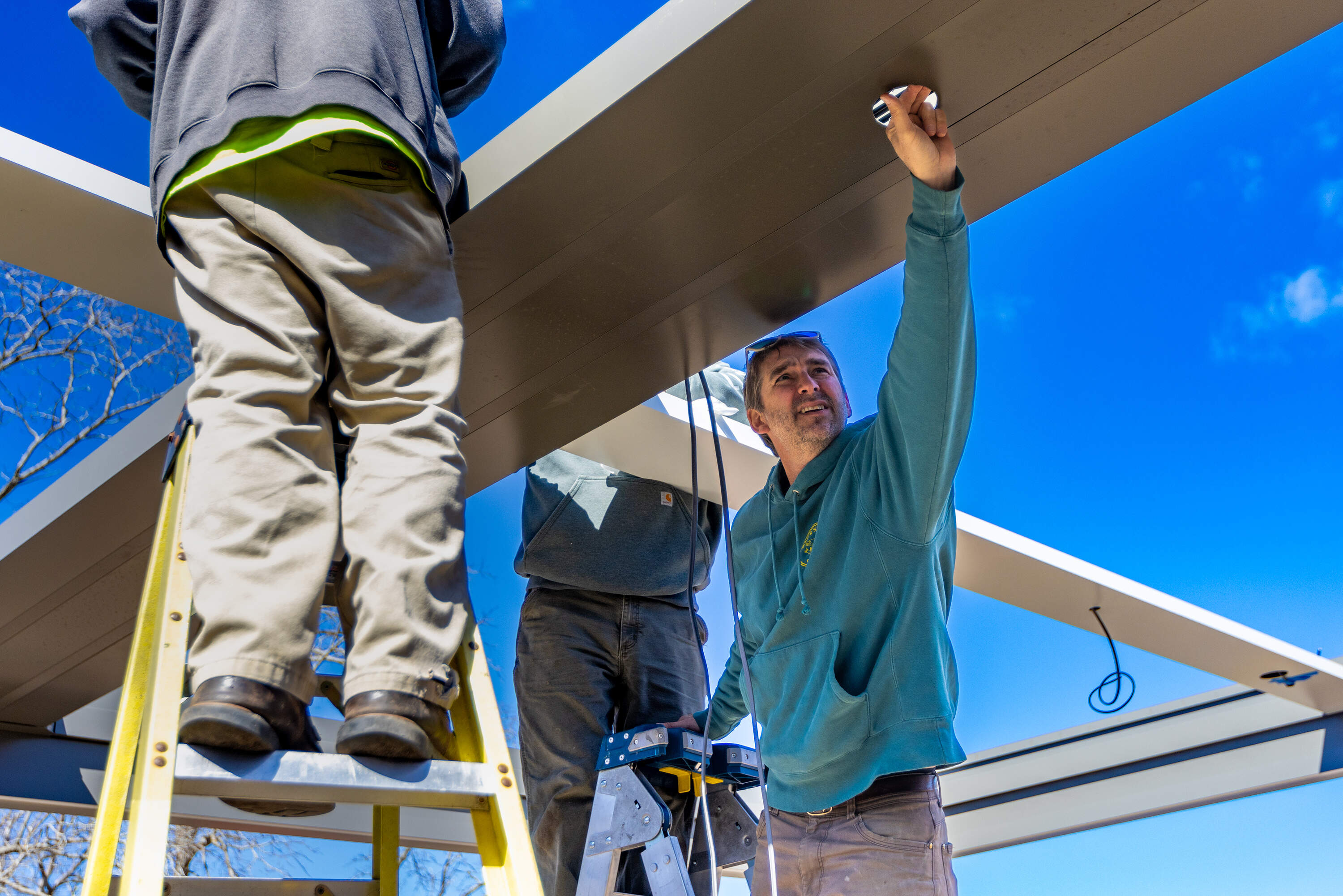 Mac Hay stands on a ladder to inspect an area where a light fixture will be installed during the renovation he is doing at his restaurant Mac’s Shack in Wellfleet. (Jesse Costa/WBUR)