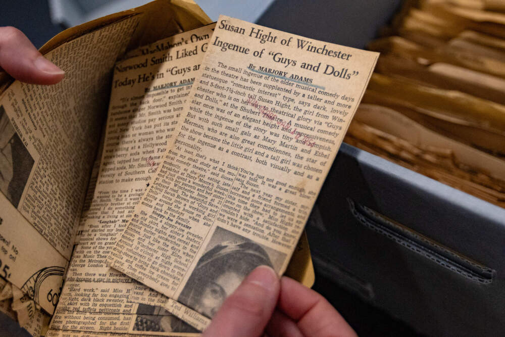 The author pulls out an article among several reviews of the theatrical production of “Guys And Dolls” at the Shubert Theater in New York City written by Boston Globe film critic Marjory Adams. (Jesse Costa/WBUR)