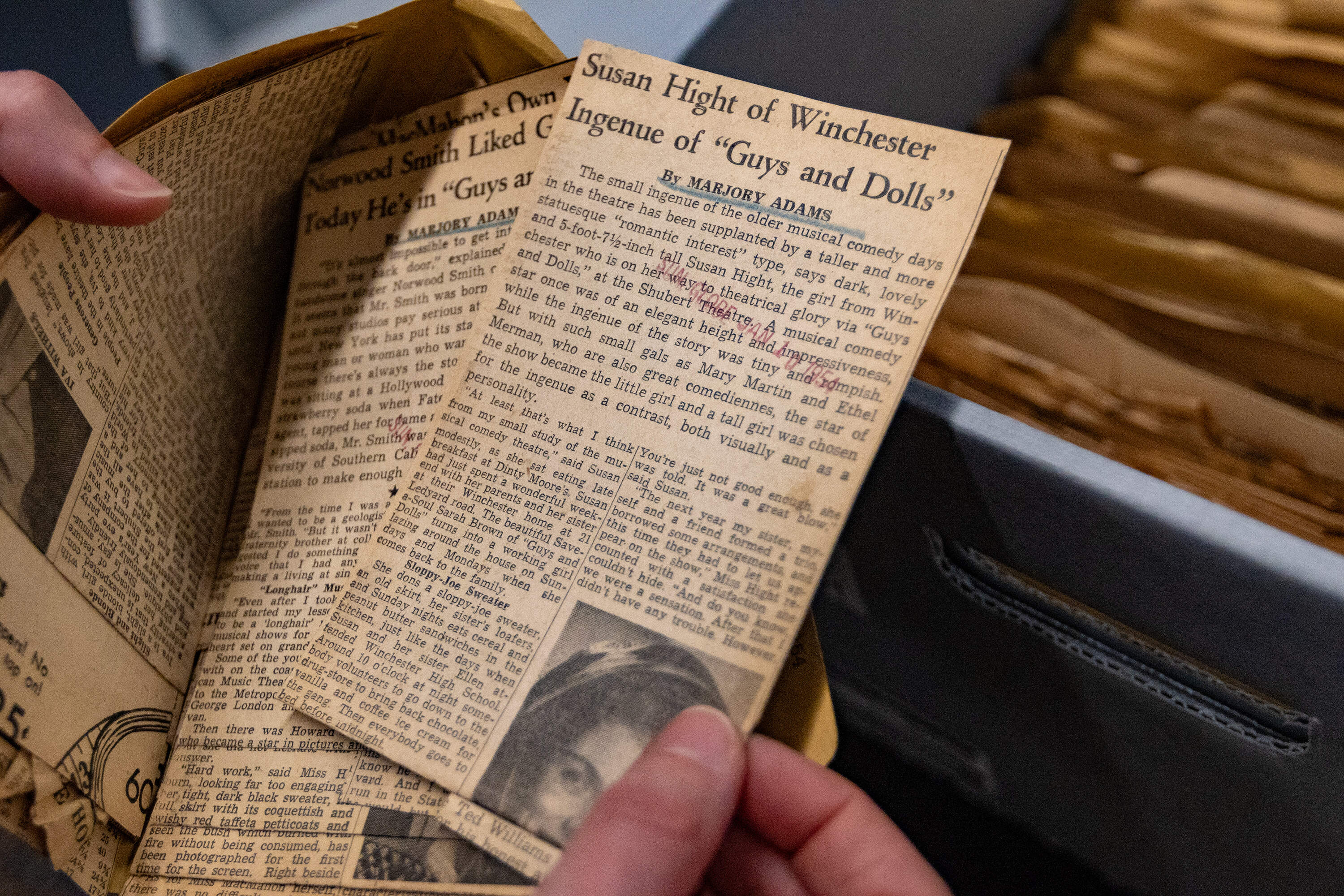 The author pulls out an article among several reviews of the theatrical production of “Guys And Dolls” at the Shubert Theater in New York City written by Boston Globe film critic Marjory Adams. (Jesse Costa/WBUR)
