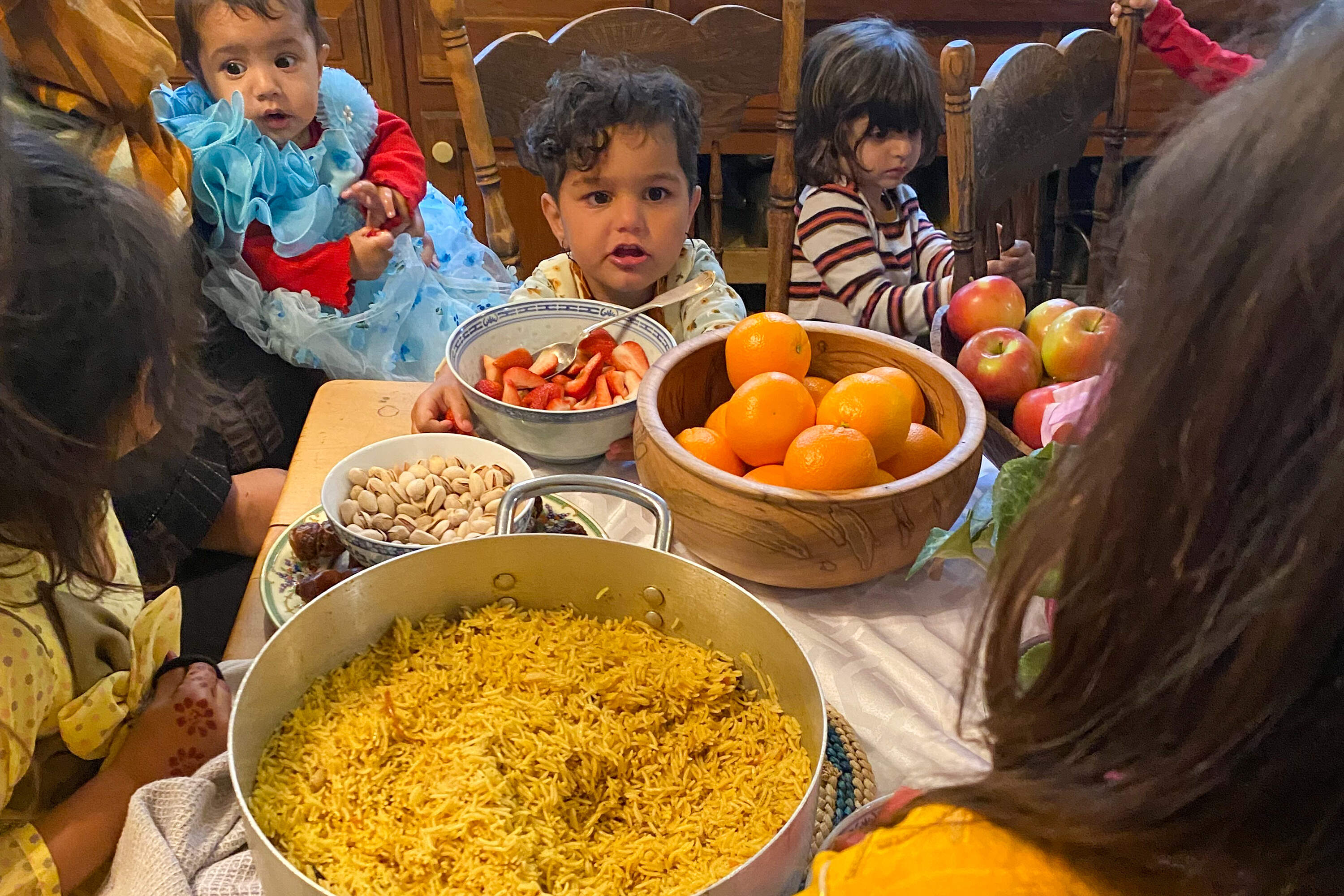 Children watch as the adults prepare dinner to celebrate Eid in the kitchen of The House of Peace in Ipswich. (Deborah Becker/WBUR)