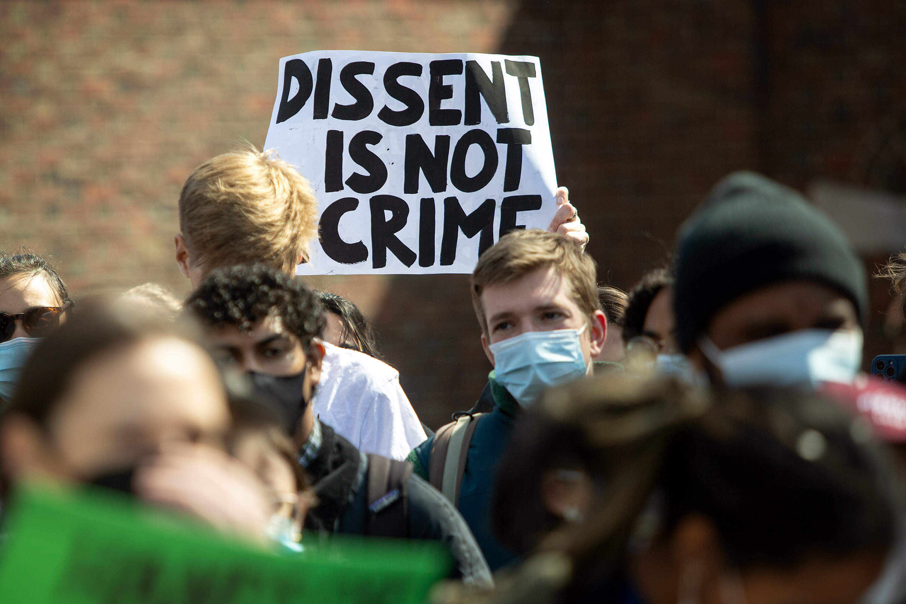 Protesters hold up signs as they march around Harvard University . (Robin Lubbock/WBUR)
