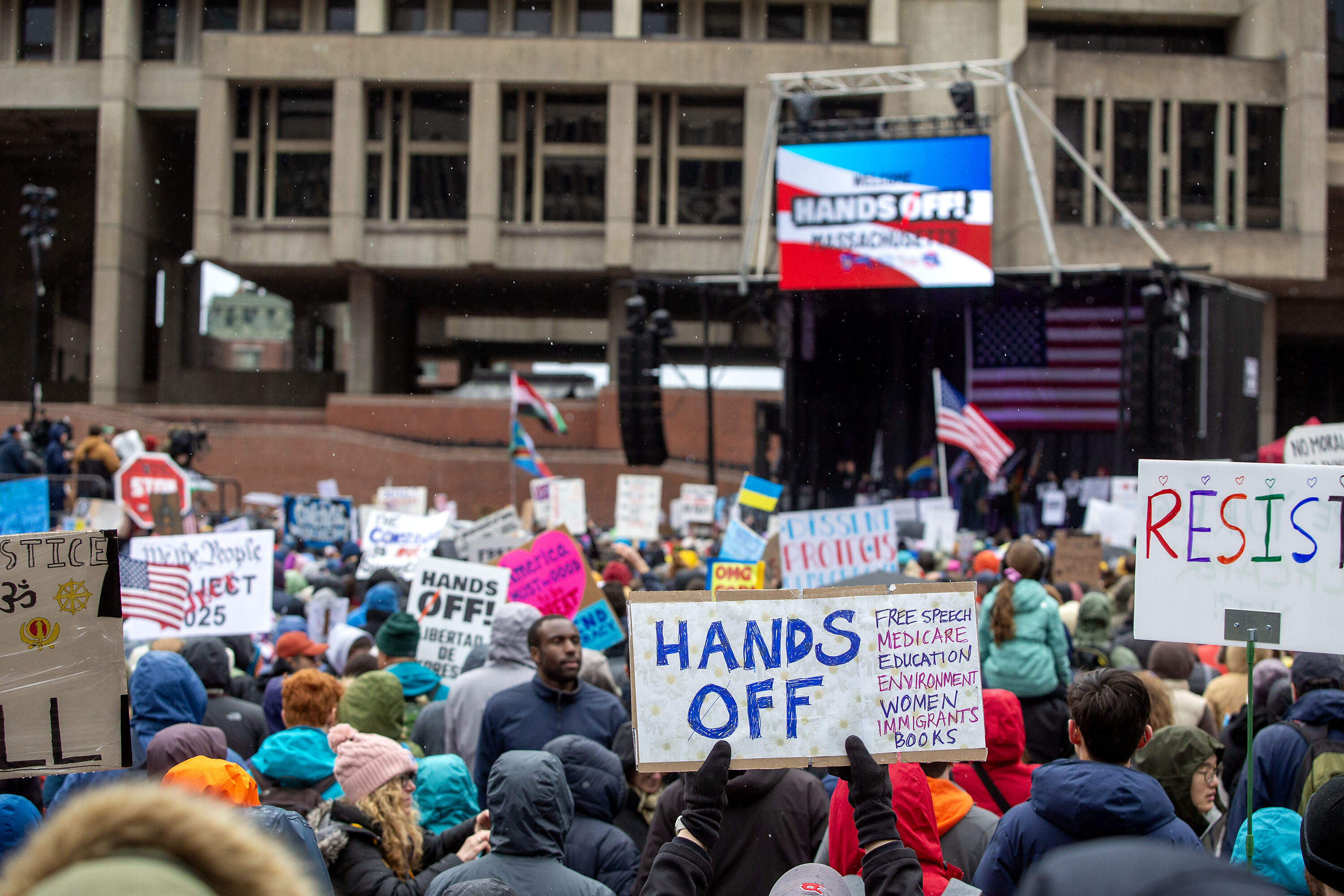 "Hands Off Massachusetts!" protesters hold up signs in City Hall Plaza in Boston. (Robin Lubbock/WBUR)
