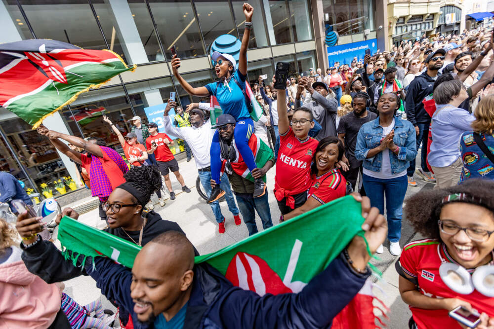 A group of Kenyan spectators celebrate at the finish line after Hellen Obiri wins the Boston Marathon in 2024. (Jesse Costa/WBUR)