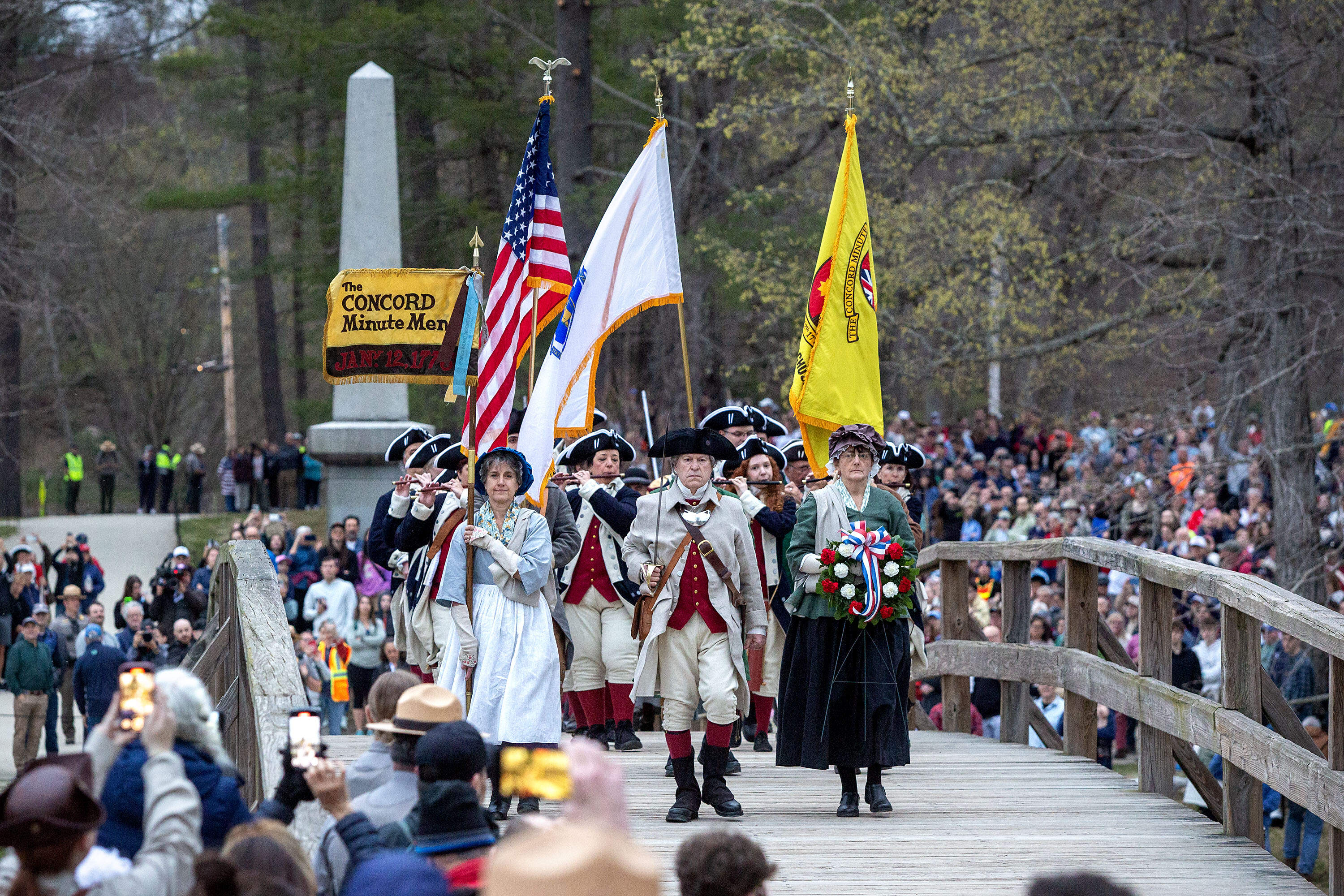 The Concord Minutemen cross the Old North Bridge at the start of Concord's commemoration the 250th anniversary of American Revolution. (Robin Lubbock/WBUR)
