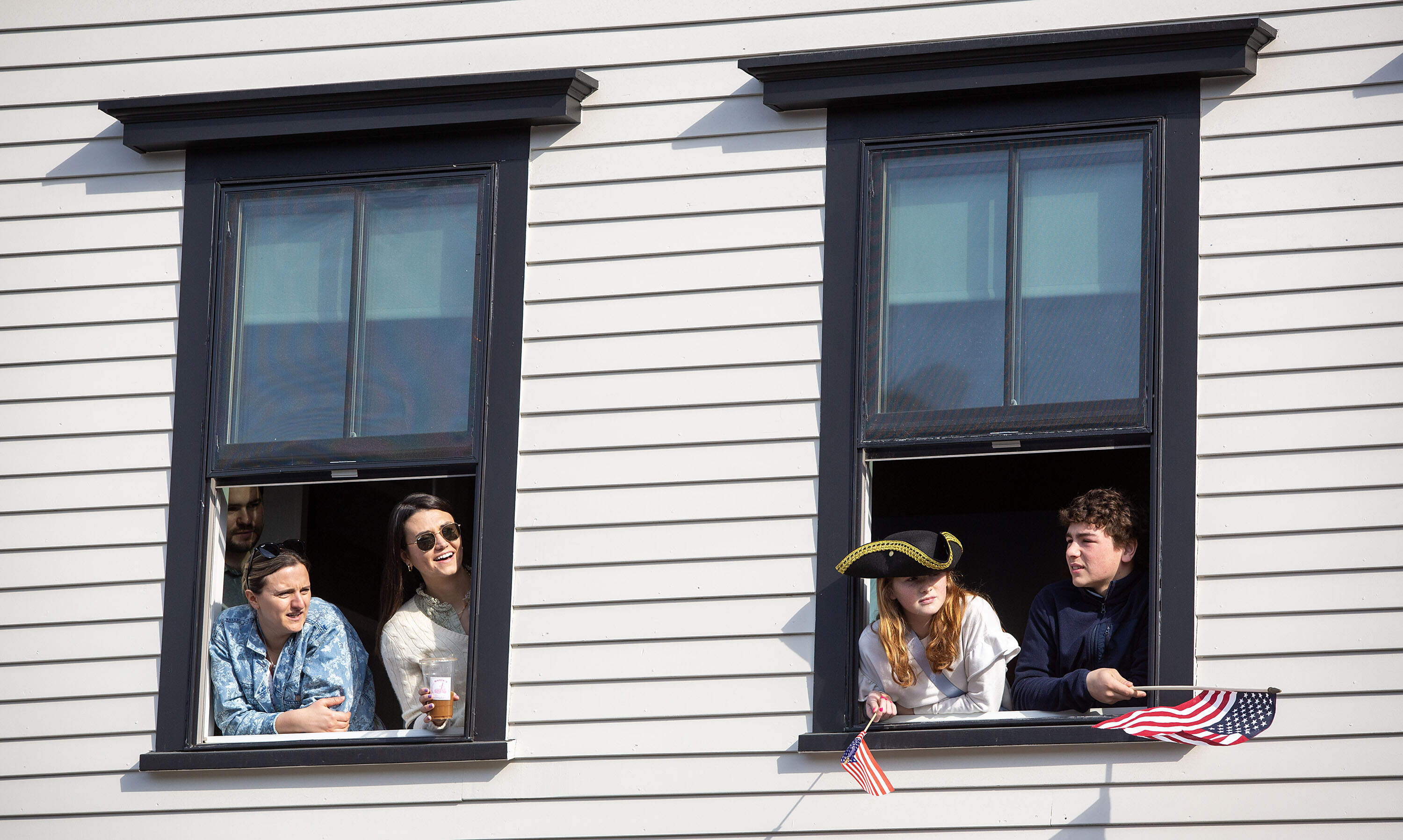 People lean out of windows on Main Street in Concord to watch the parade in commemoration of the 250th anniversary of the Battle of Concord. (Robin Lubbock/WBUR)