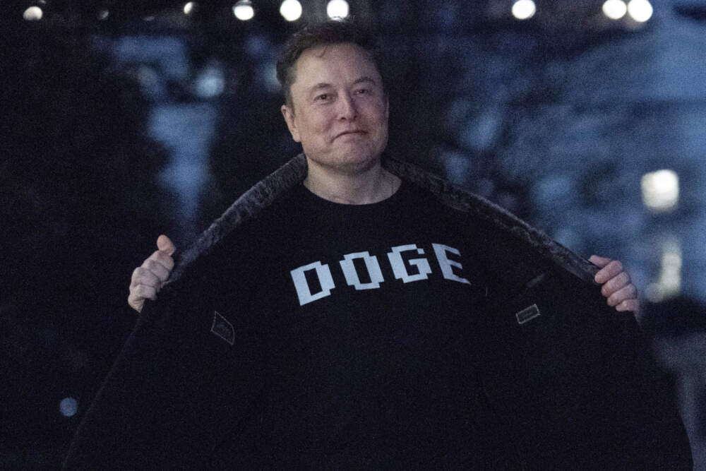 Elon Musk flashes his T-shirt that reads "DOGE" to the media as he walks on South Lawn of the White House, in Washington, March 9, 2025. (Jose Luis Magana/AP)