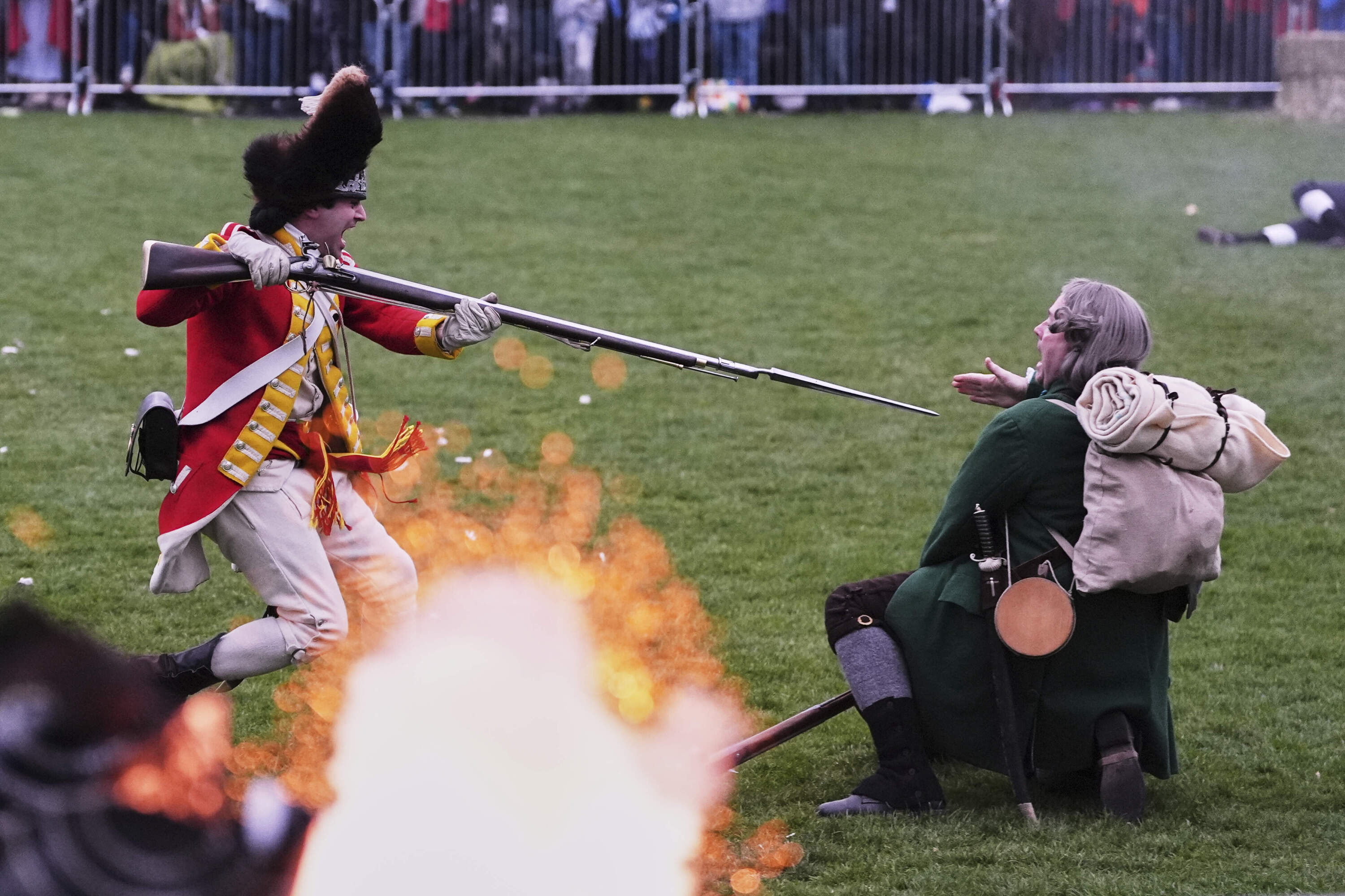 While a rifle fires, a British Regular stabs a New England colonial militia, also known as a Minute Man, during a reenactment celebration of the 250th anniversary of the Battle of Lexington and start of the American Revolution, Saturday, April 19, 2025, in Lexington. (Charles Krupa/AP)