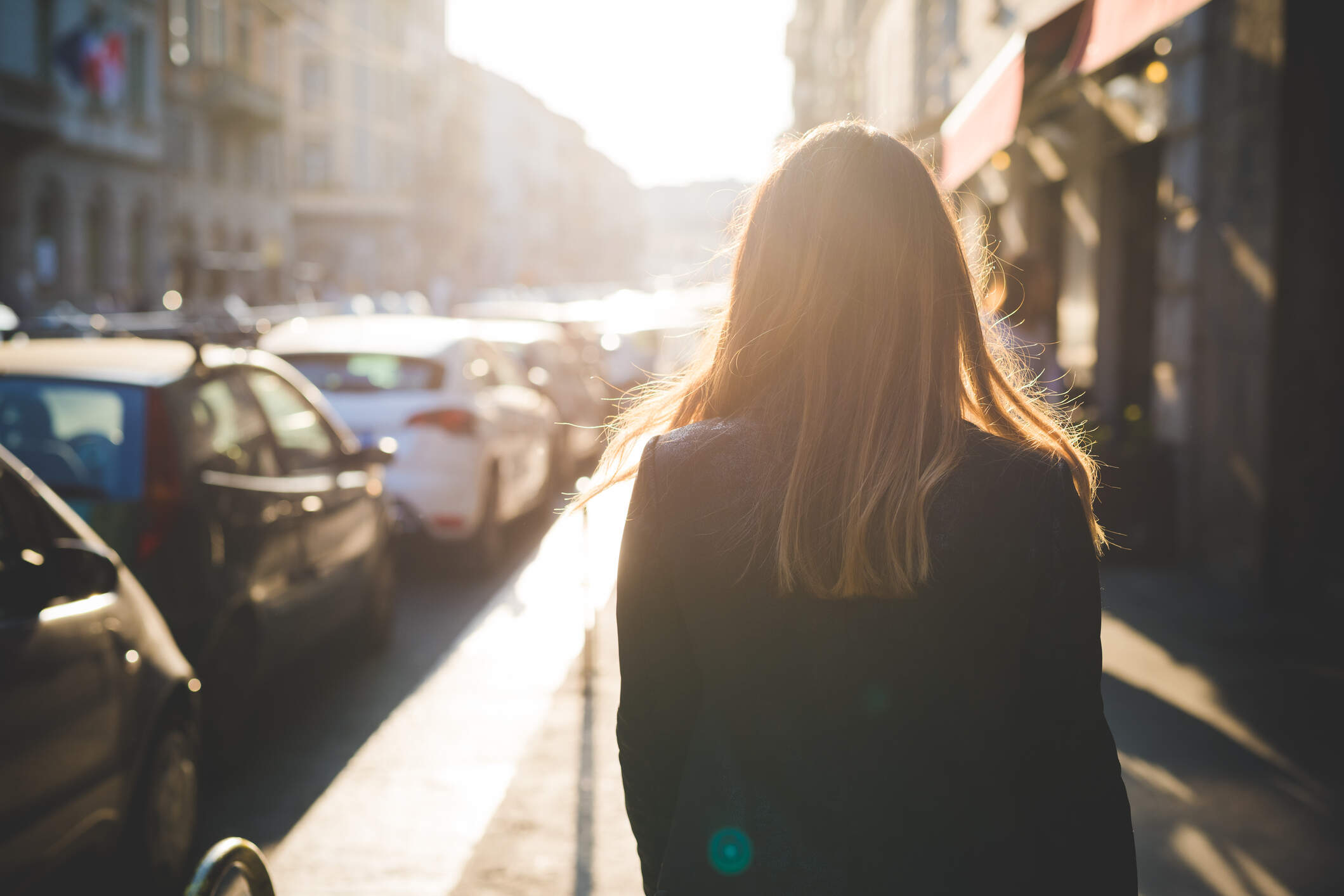 Rear view of young woman strolling on city street. (Getty Images)