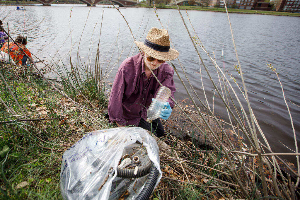 A volunteer removes garbage and debris from the Charles River in Cambridge in 2017. (Keith Bedford/The Boston Globe via Getty Images)