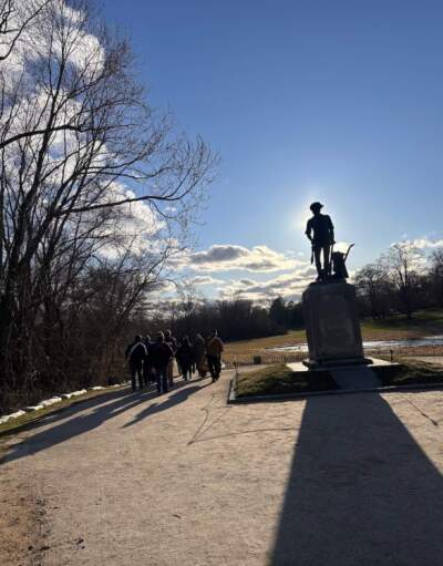 The Concord Minute Men, rehearsing for the 250th celebration, march by the Minute Man Statue sculpted by Daniel Chester French near the Old North Bridge. (Courtesy Cloe Axelson)