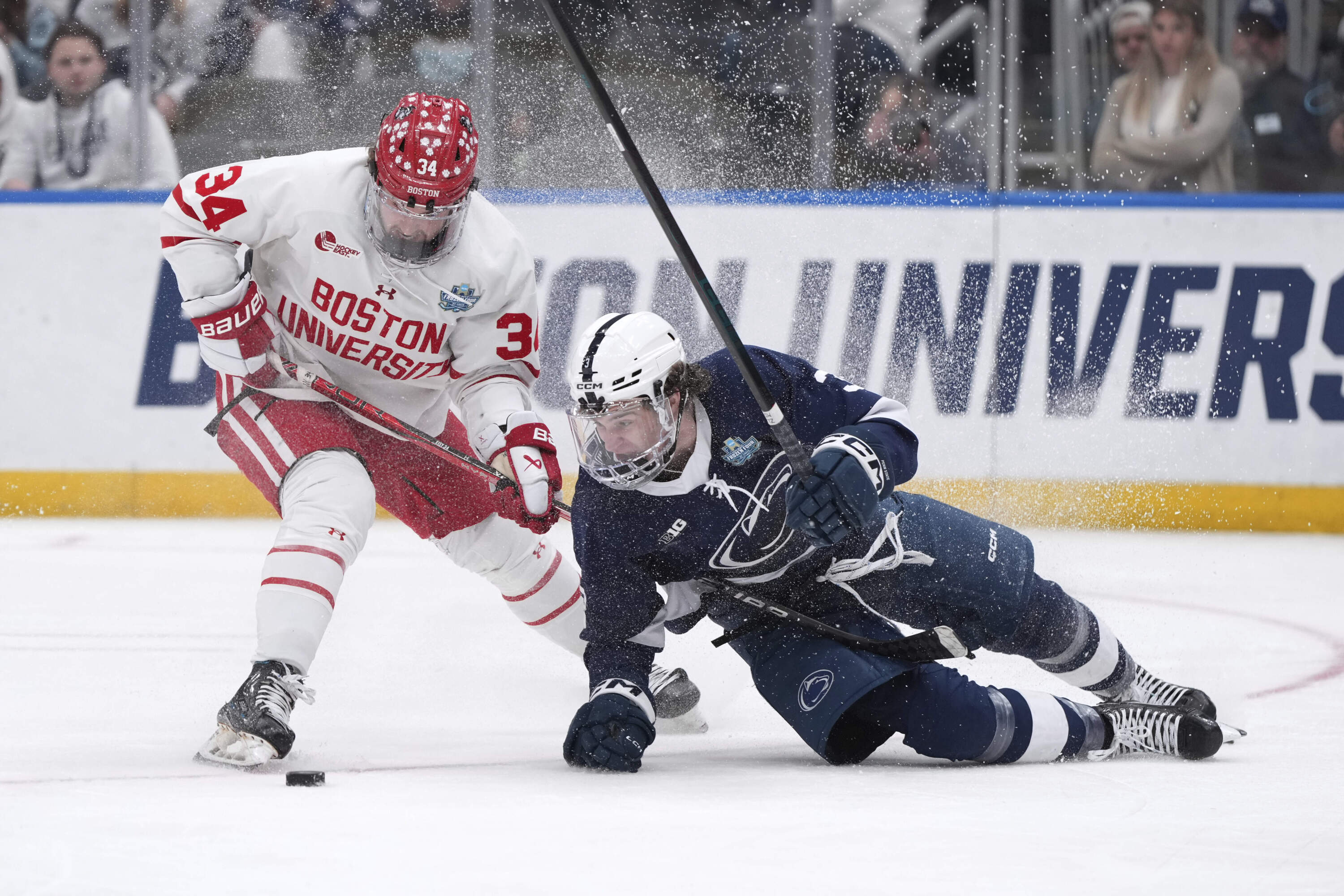 Penn State's Casey Aman, right, falls after colliding with Boston University's Cole Eiserman during the third period in a semifinal game in the NCAA Frozen Four men's college hockey tournament, Thursday, April 10, 2025, in St. Louis (Jeff Roberson/AP)