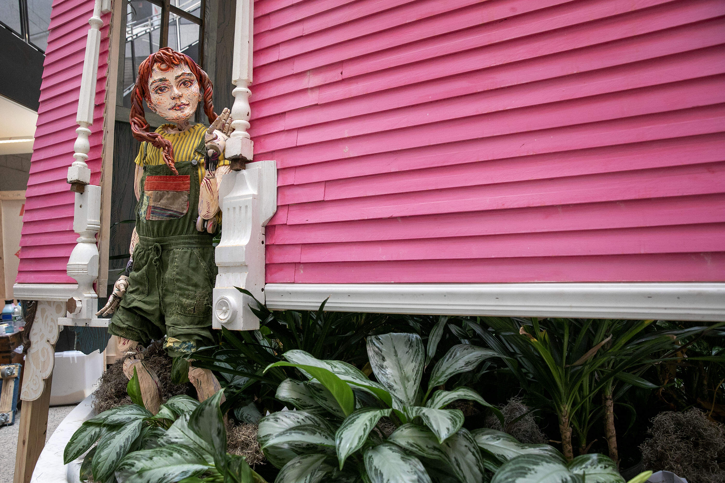 Terra, a character from Swoon's story about the Sibylant Sisters, steps through a doorway of the installation of the Sibylant House at the Boston Public Library. (Robin Lubbock/WBUR)