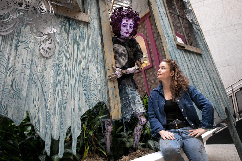 Artist Caledonia Curry, known as Swoon, sits by the her Triennial installation at the Boston Public Library. (Robin Lubbock/WBUR)