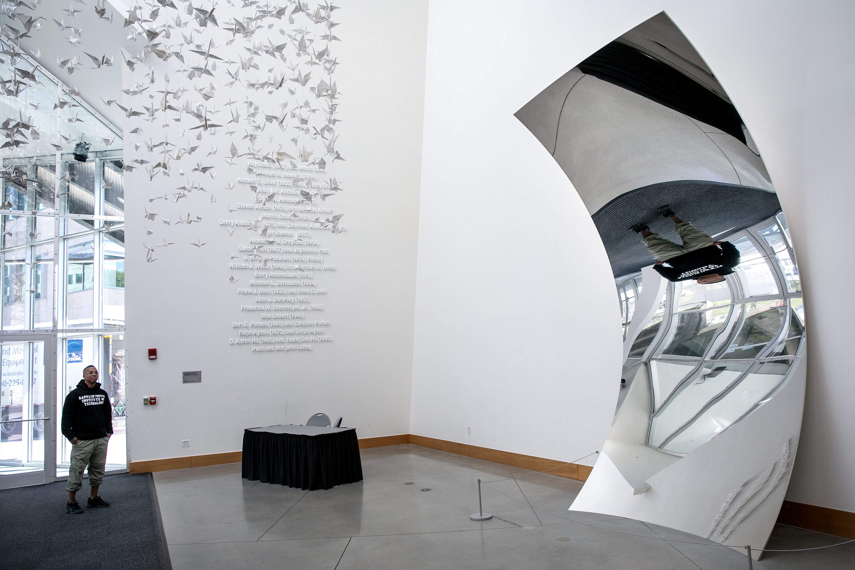 Rapper Lupe Fiasco admires Anish Kapoor's Non-Object (Plane), a reflecting steel installation at MIT's Stata Center. (Robin Lubbock/WBUR)