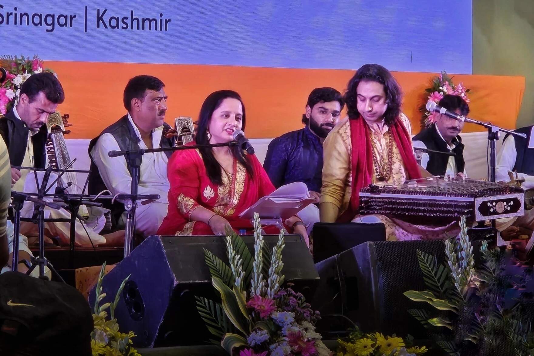 Hindu Kashmiri Pandit poet and songwriter Sunayana Kachroo (in red) directed, narrated, and performed in Srinagar, Kashmir, July 6, 2024. Pandit Abhay Ruston Sopori (in a gold kurta) performed on the santoor. They are accompanied by classical Kashmiri musicians. (Courtesy of Sunayana Kachroo via Connecticut Public)