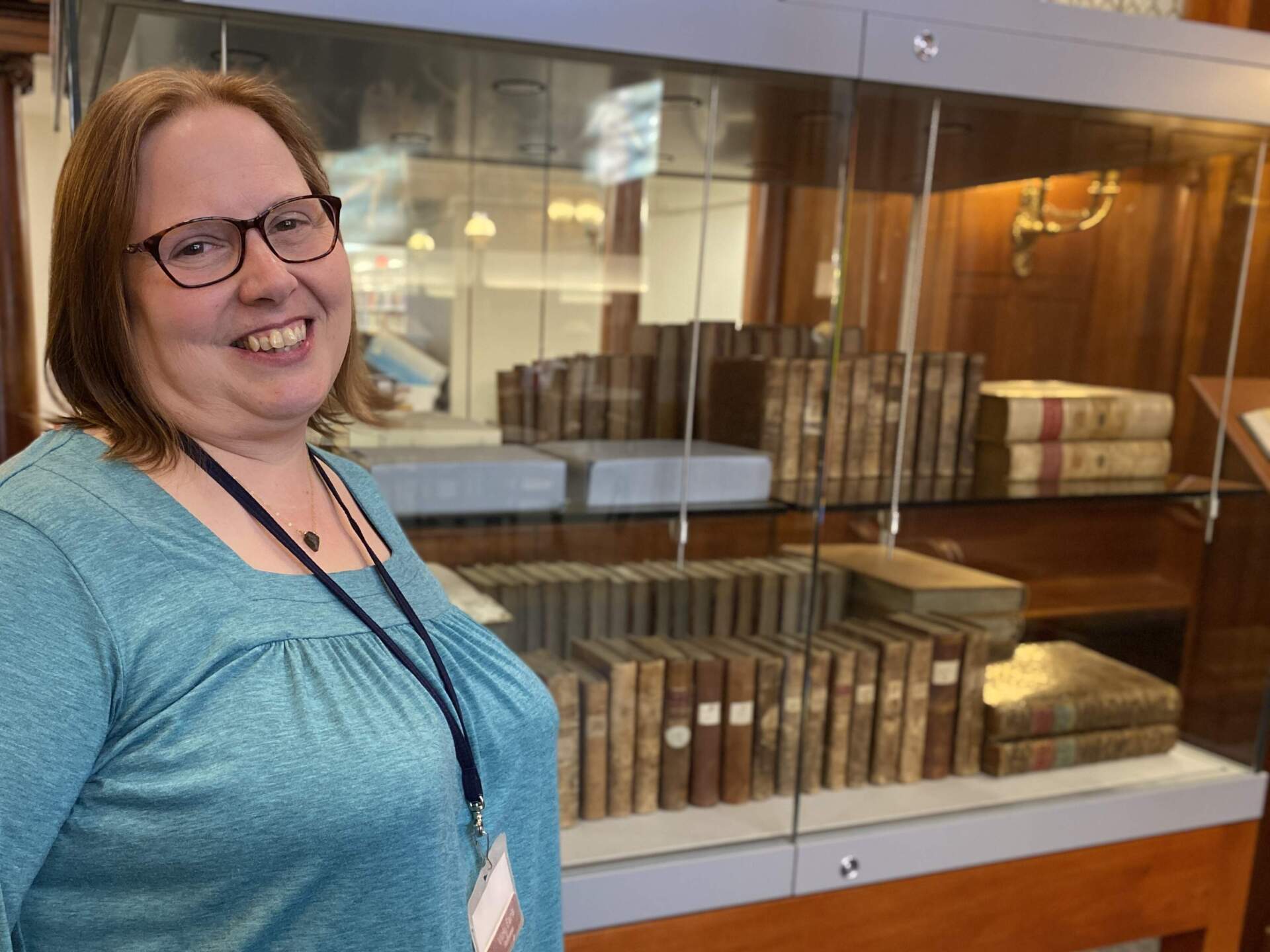 Librarian Vicki Earls stands in front of a collection of books donated by Benjamin Franklin to the town of Franklin's public library. (Sharon Brody/WBUR)