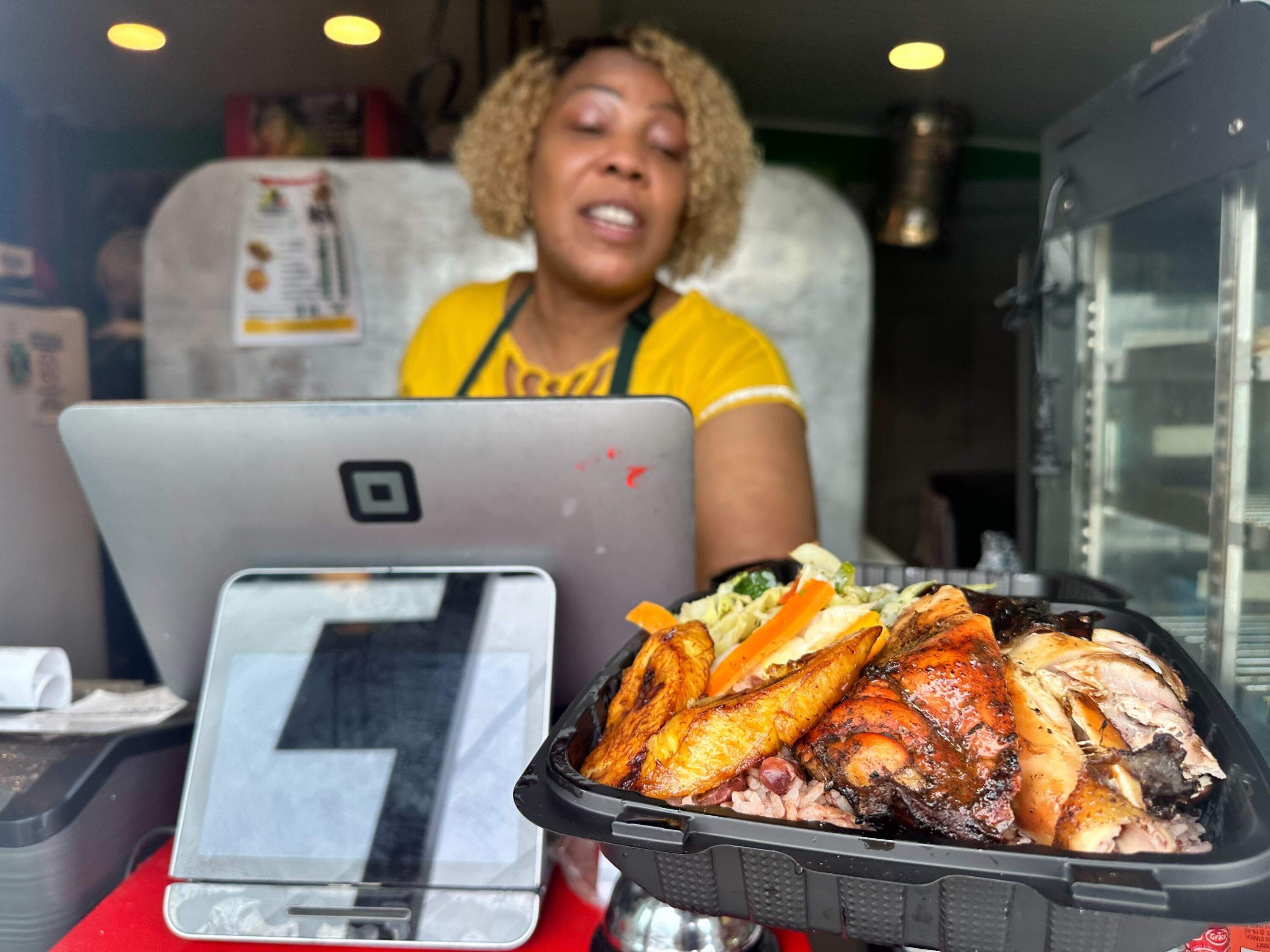 Stacy Thomas Waite, owner of Vineyard Caribbean Cuisine, offers up a plate of jerk chicken. (Simón Rios/WBUR)