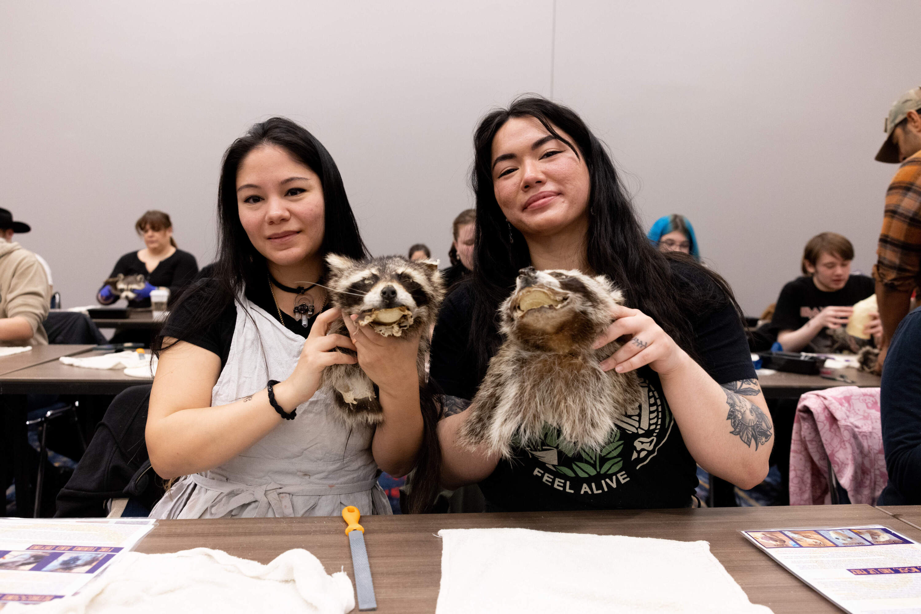 Two expo attendees pose with raccoon pelts during a taxidermy class. (Courtesy of Michelle Cozzaglio)