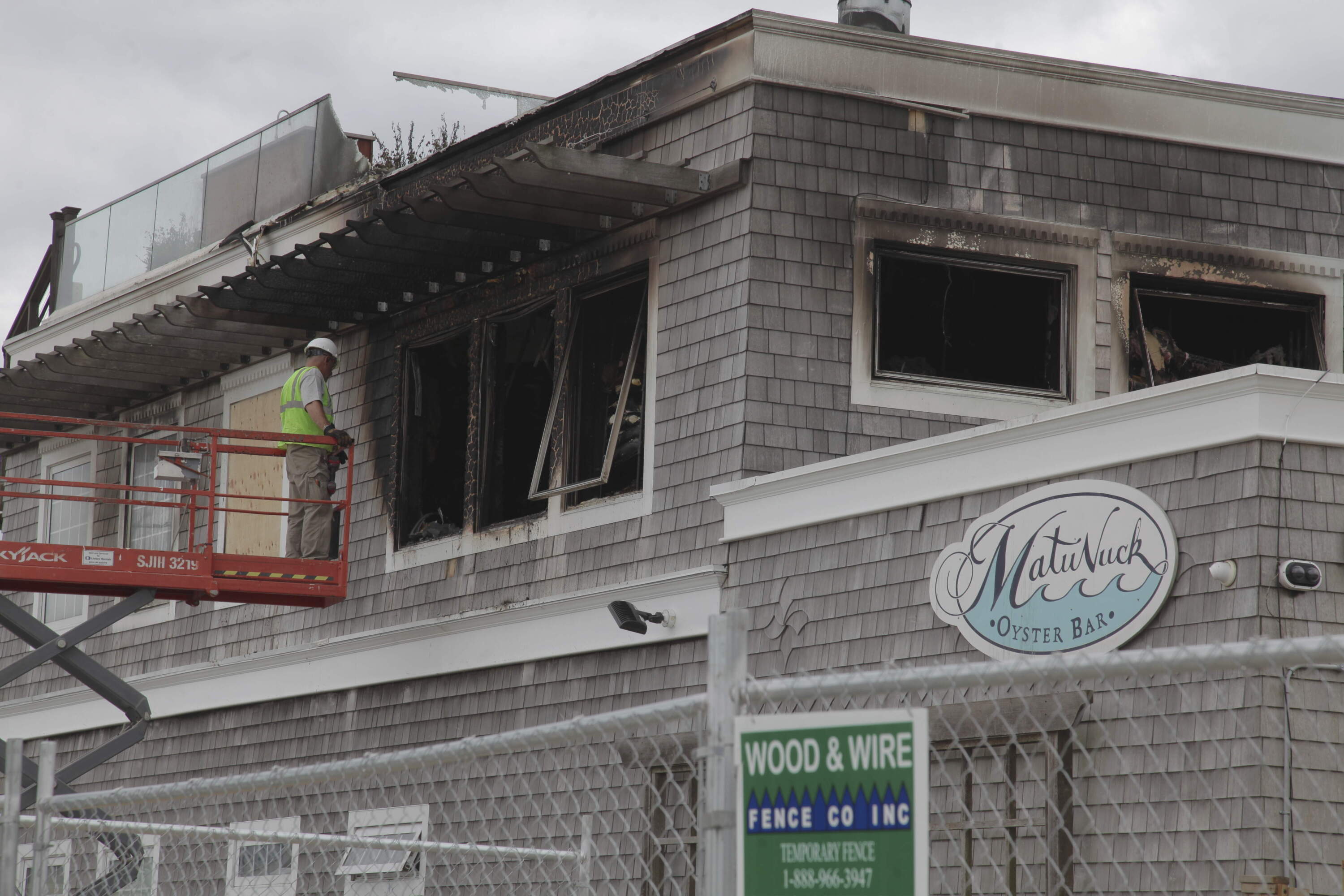 Crews work on boarding up broken windows after a fire damaged Matunuck Oyster Bar in South Kingston, R.I. on Tuesday, May 20, 2025. (Kimberlee Kruesi/AP)