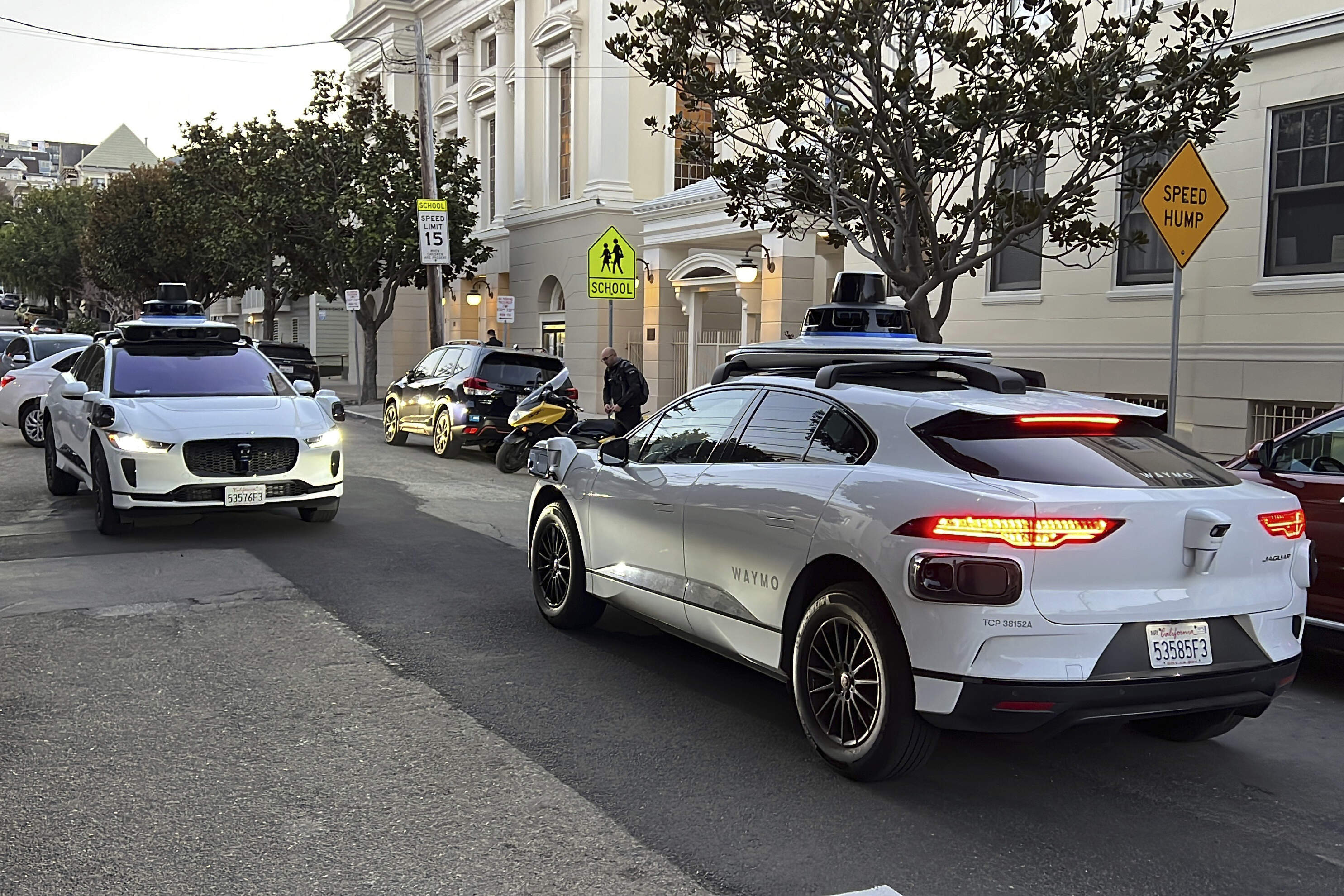 Two Waymo driverless taxis stop before passing one another on a San Francisco street in 2023.